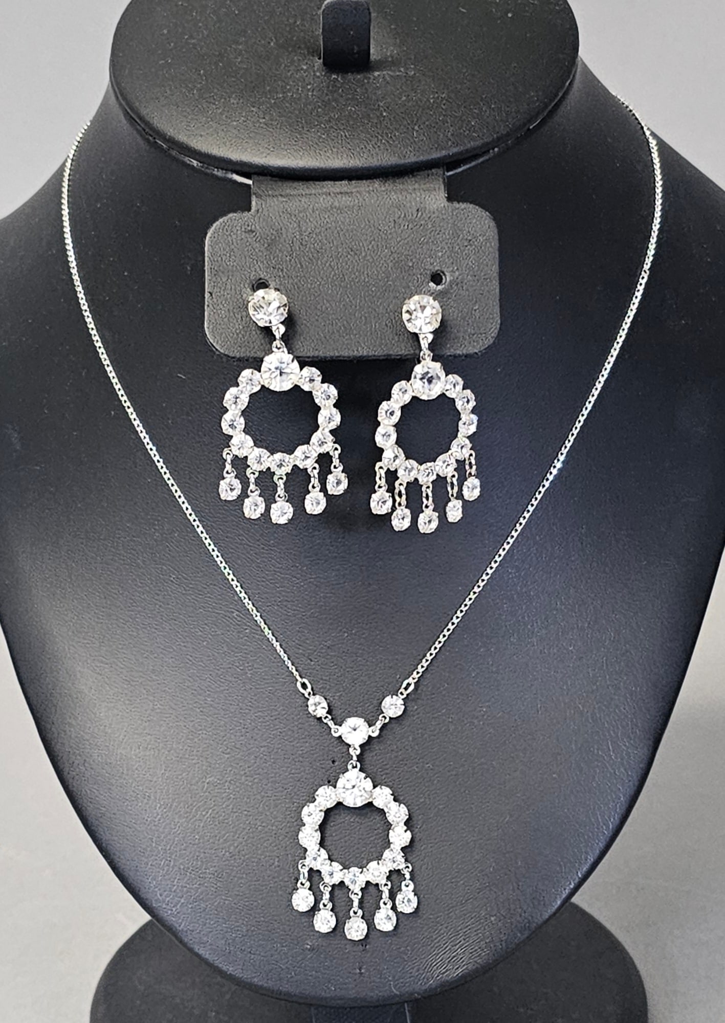 Sterling Clear Rhinestone Necklace & Earrings 9.5 Grams: This vintage jewelry set comprises a matching necklace and a pair of non-pierced screw-back earrings. Each piece is constructed in sterling silver and features a circular wreath-shaped motif. The