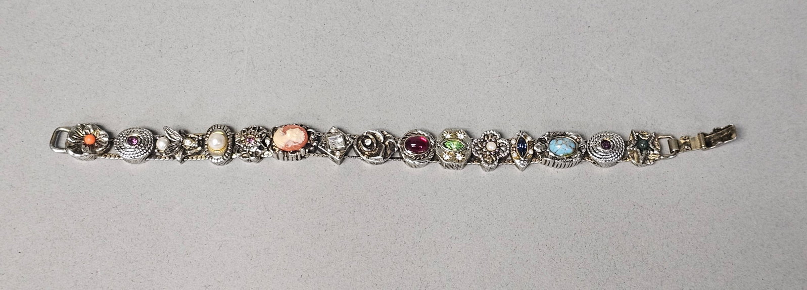 Victorian Revival Multi-Stone Slide Bracelet: This vintage Victorian Revival slide style bracelet features 15 decorative links set on a double-row mesh chain. The piece is constructed from silver-tone base metal with gold-tone accents. The bracel