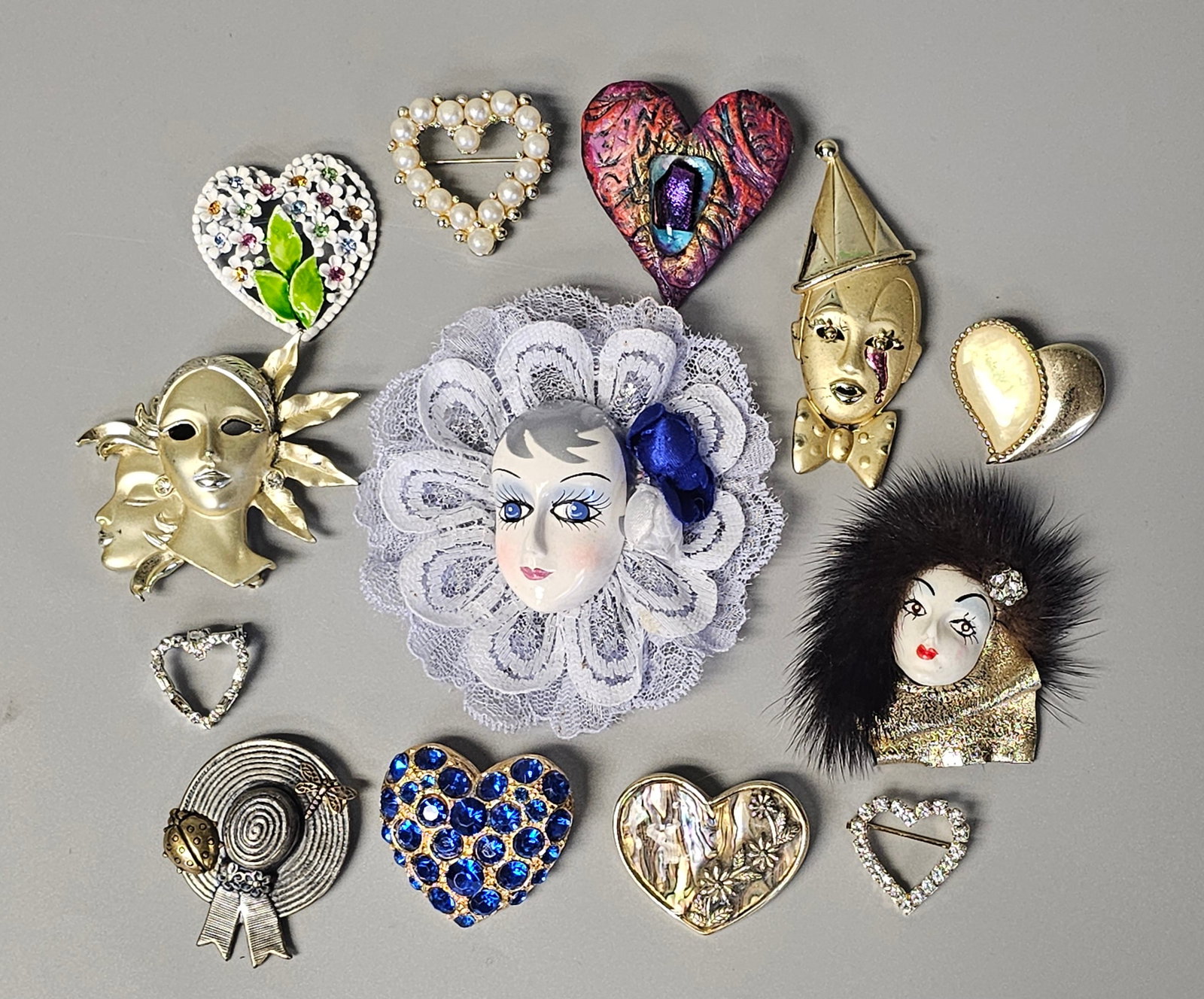 Vintage Costume Brooches Inc Theatrical Masks: This lot features thirteen vintage costume jewelry brooches primarily focused on theatrical characterizations and varied heart designs. The collection is in overall good vintage condition. Minor surfa