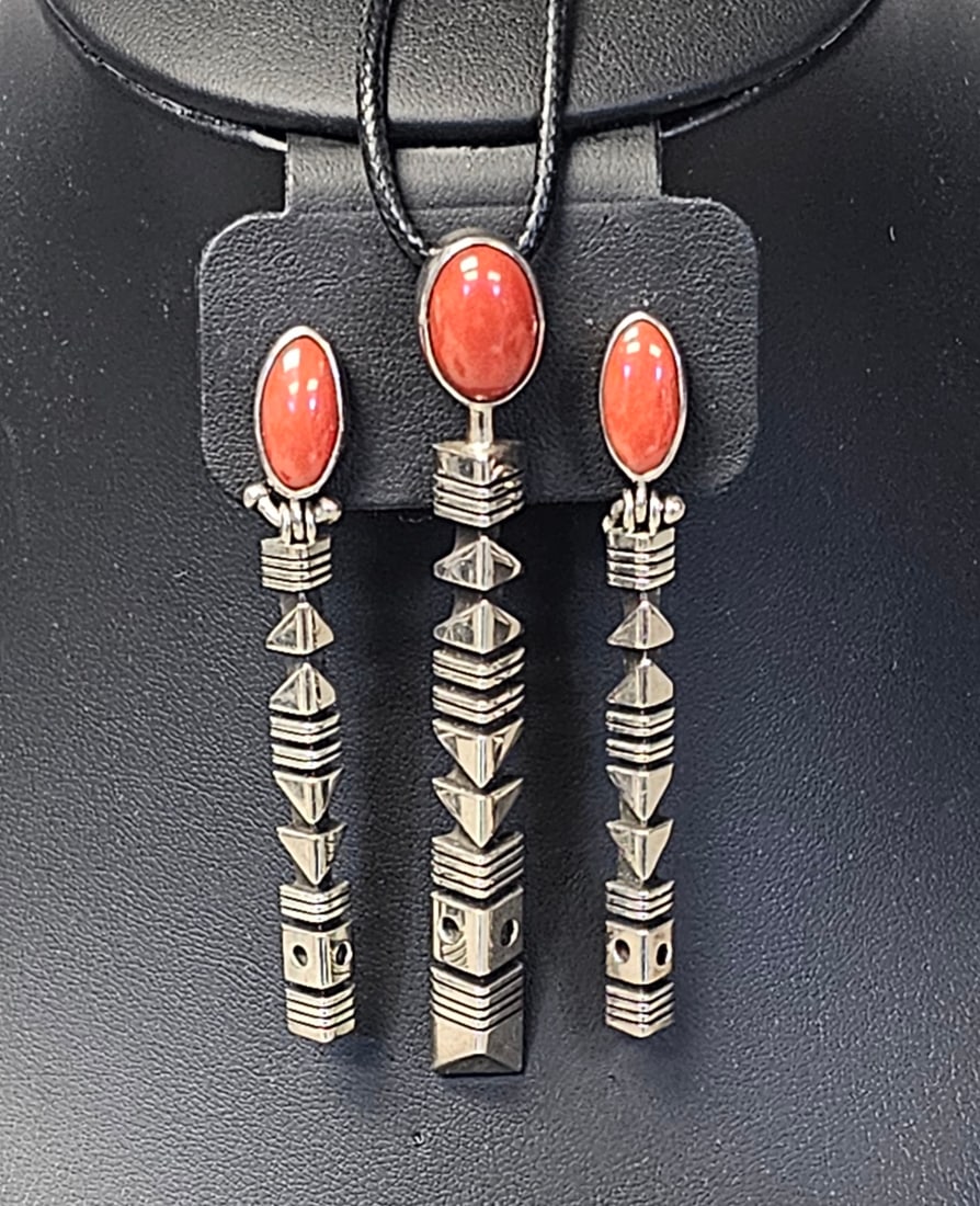 Charles Ortiz Taos Pueblo Sterling Coral Set 33.5 Grams: A three piece jewelry set by Taos Pueblo artist Charles Ortiz, including a pendant and a matched pair of long drop earrings. The set features a modernist geometric design. The back of each piece is