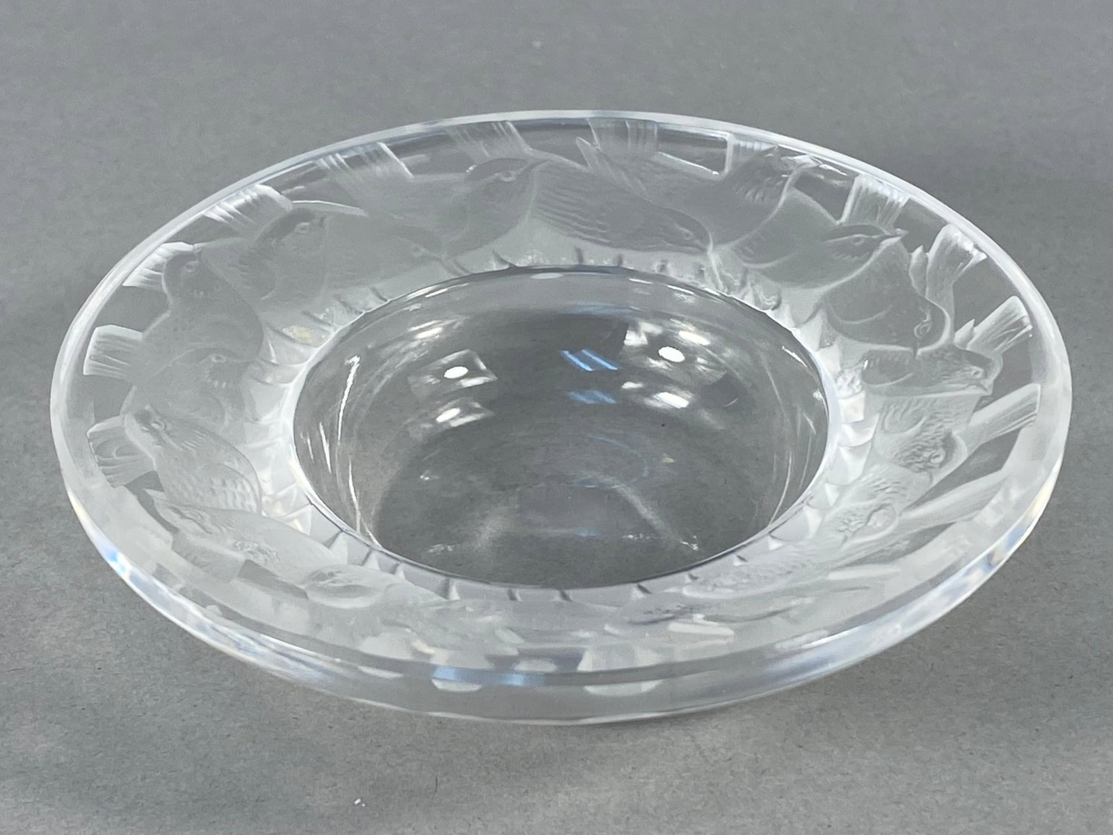 Lalique France Crystal Pinsons Bird Dish: This is a circular dish crafted from frosted and clear crystal by Lalique, France. The piece is decorated in the Pinsons pattern, which consists of a continuous relief band of finches nested within