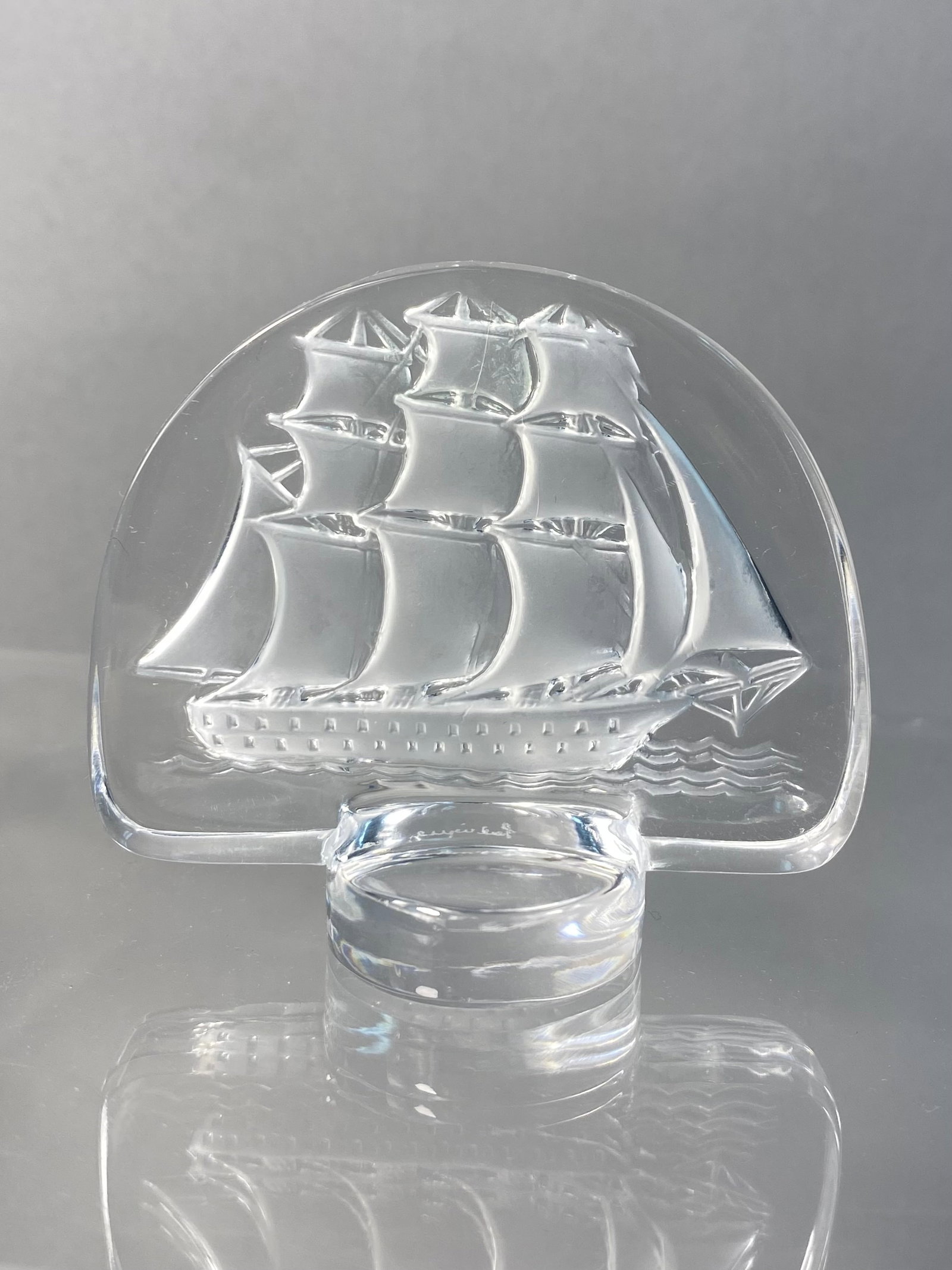 Lalique France Crystal Caravelle Sailing Ship Paperweight: This Lalique crystal paperweight, identified as the Caravelle pattern, features a detailed three-masted sailing ship depicted in intaglio on the reverse of a clear, semi-circular crystal plaque. The