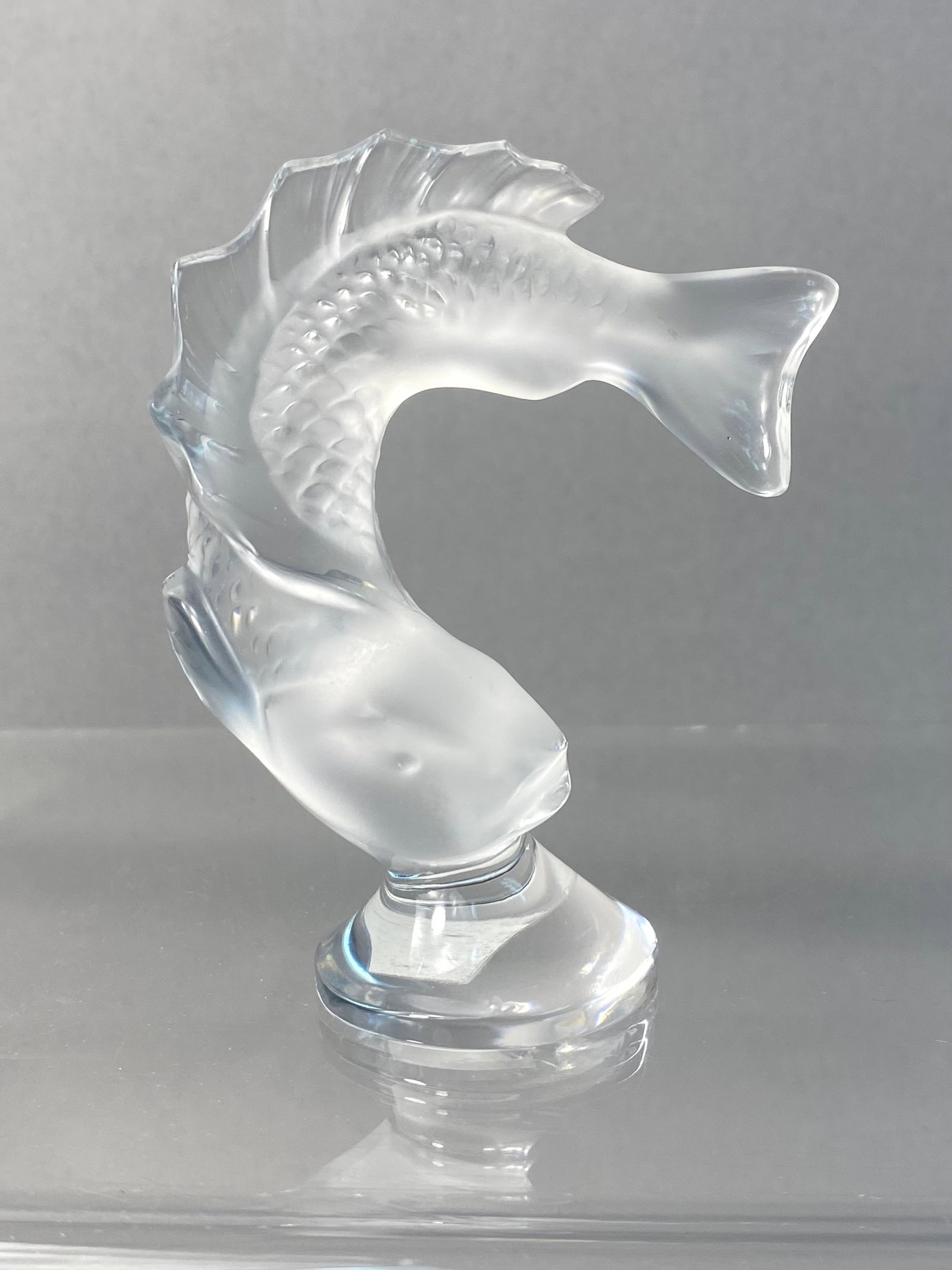 Lalique France Crystal Goujon Fish Figurine: A Lalique France crystal figurine titled Goujon, depicting a fish in a dynamic leaping pose. The piece features a frosted or satin-finished body with detailed molded scales, contrasted by clear crysta