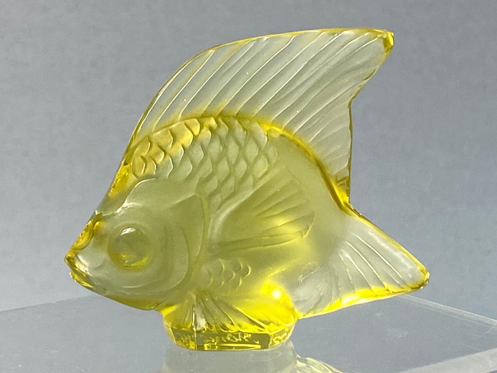Lalique Yellow Crystal Poisson Fish Figurine: This stylized tropical fish figurine is part of the iconic Poisson collection, originally designed by Rene Lalique in 1913. The piece is crafted from translucent yellow lead crystal, employing a combi