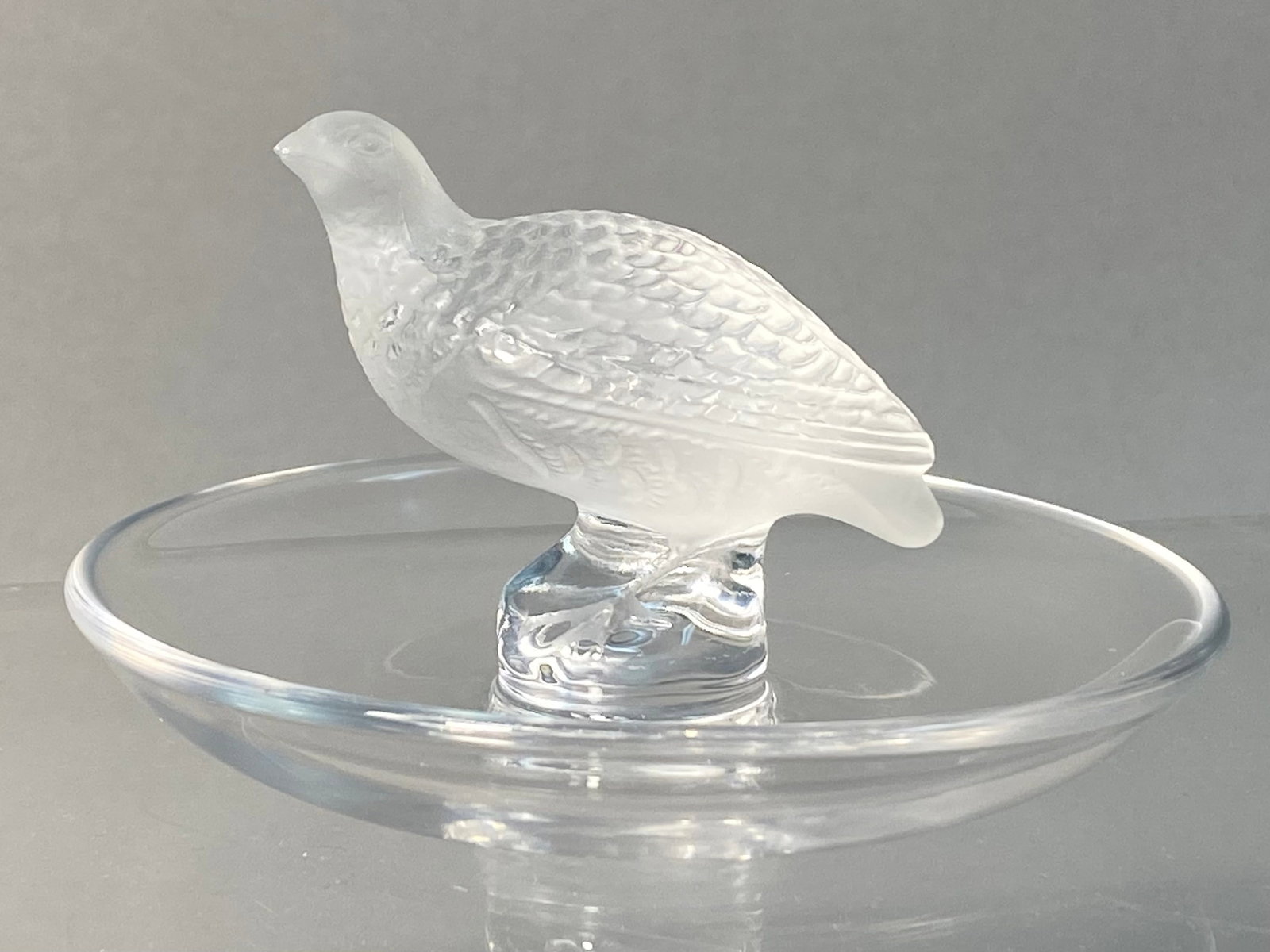 Lalique France Crystal Quail Perdrix Trinket Dish: This is a lead crystal trinket tray or ring dish featuring a central figurine of a quail, known as the Perdrix model, produced by Lalique France. The quail is rendered in frosted glass with detailed p