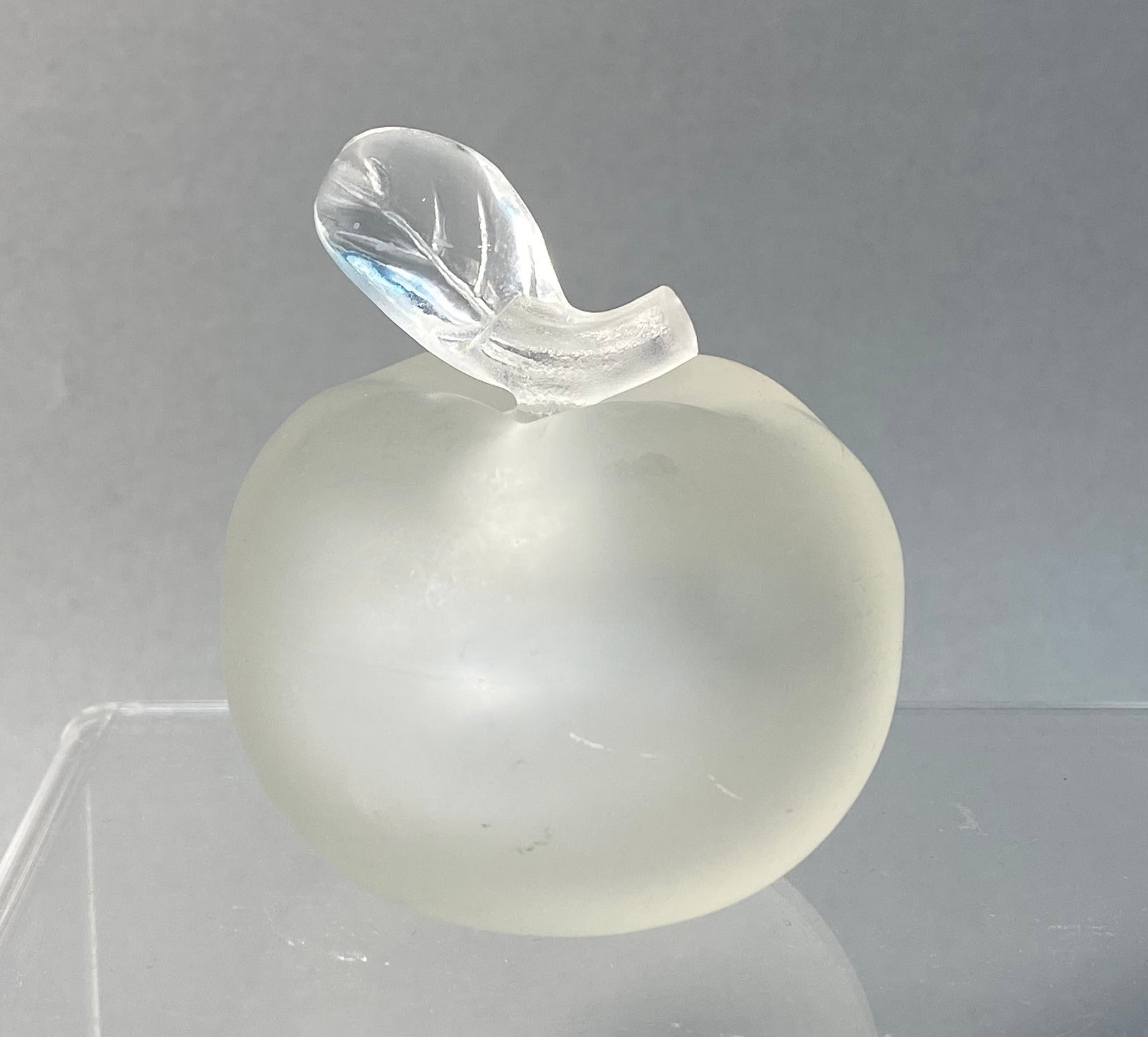 Lalique for Nina Ricci Crystal Apple-Form Perfume Bottle: A frosted crystal perfume bottle in the form of an apple, attributed to the Nina Ricci Pomme model by Lalique. The piece features a globular body with an acid-etched matte finish and a clear glass sto