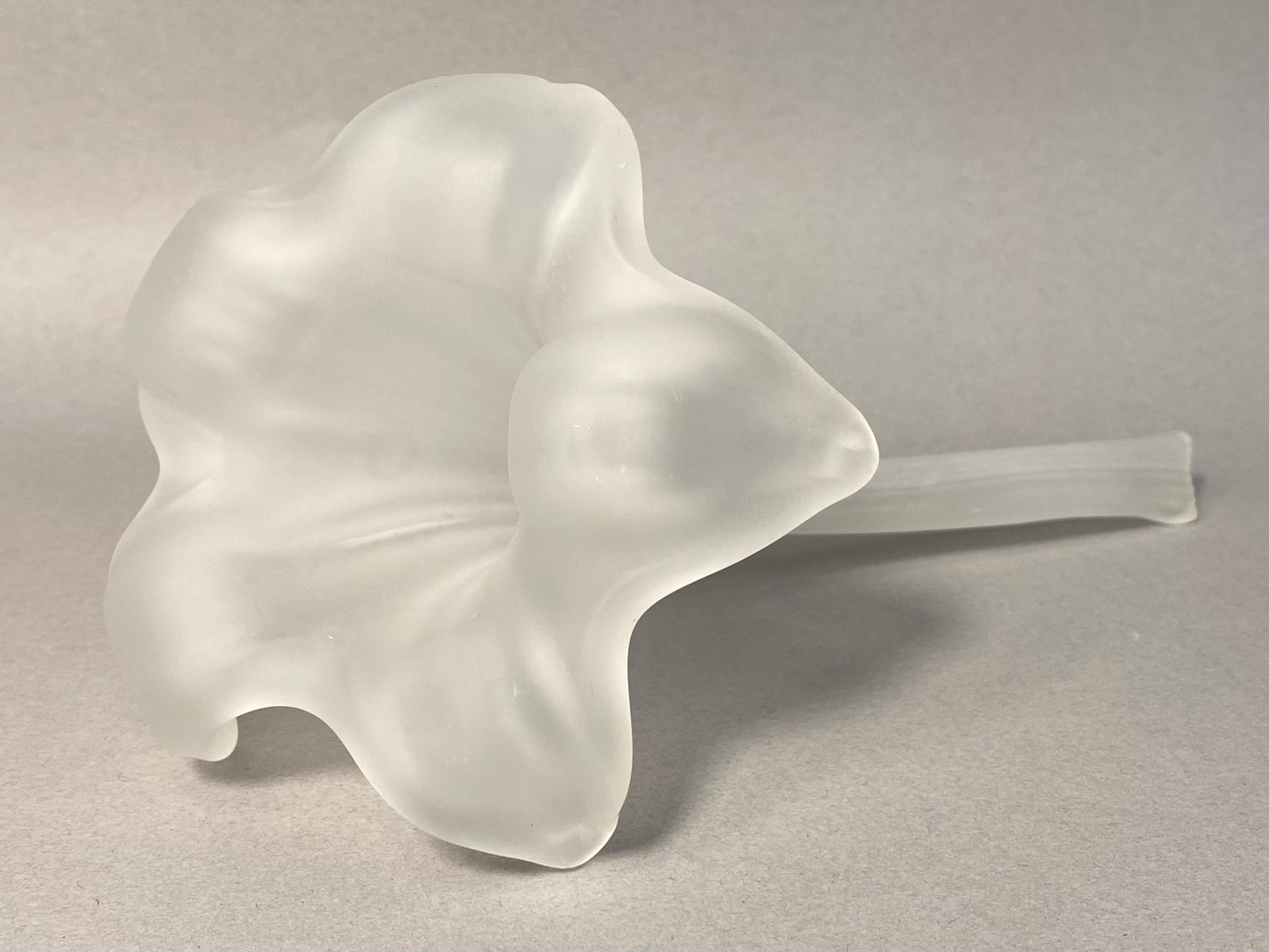 Frosted Glass Lily Flower Bud Vase: A vintage frosted glass flower sculpture in the form of a lily or trumpet flower, often utilized as a horizontal bud vase. The piece is crafted from colorless glass with a uniform acid-etched or satin