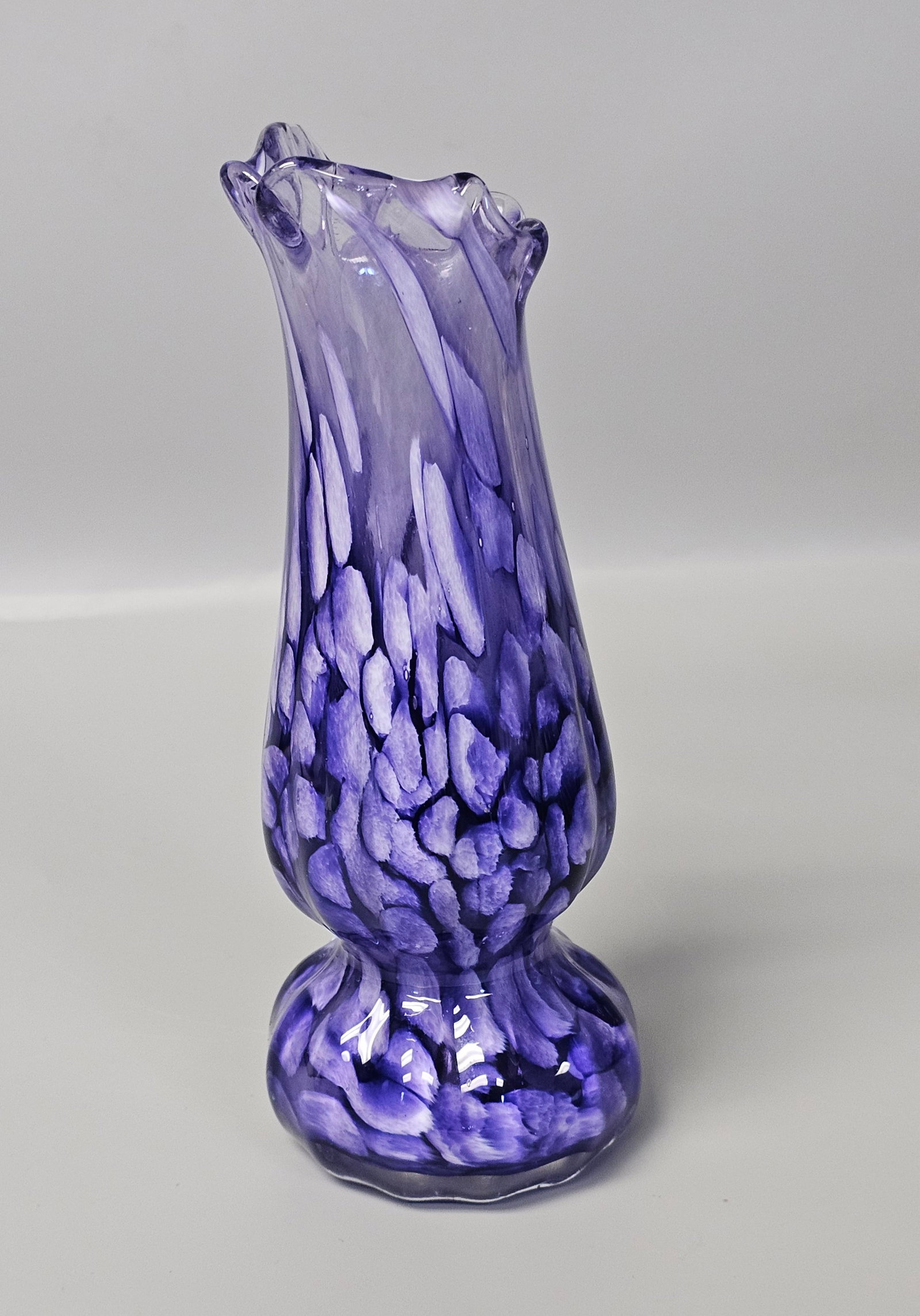 Hand-Blown Purple & White Spatter Art Glass Vase: A hand-blown art glass vase featuring a spatter or confetti-style pattern. The piece is constructed from translucent amethyst glass integrated with opaque purple and white frit inclusions. The undersi