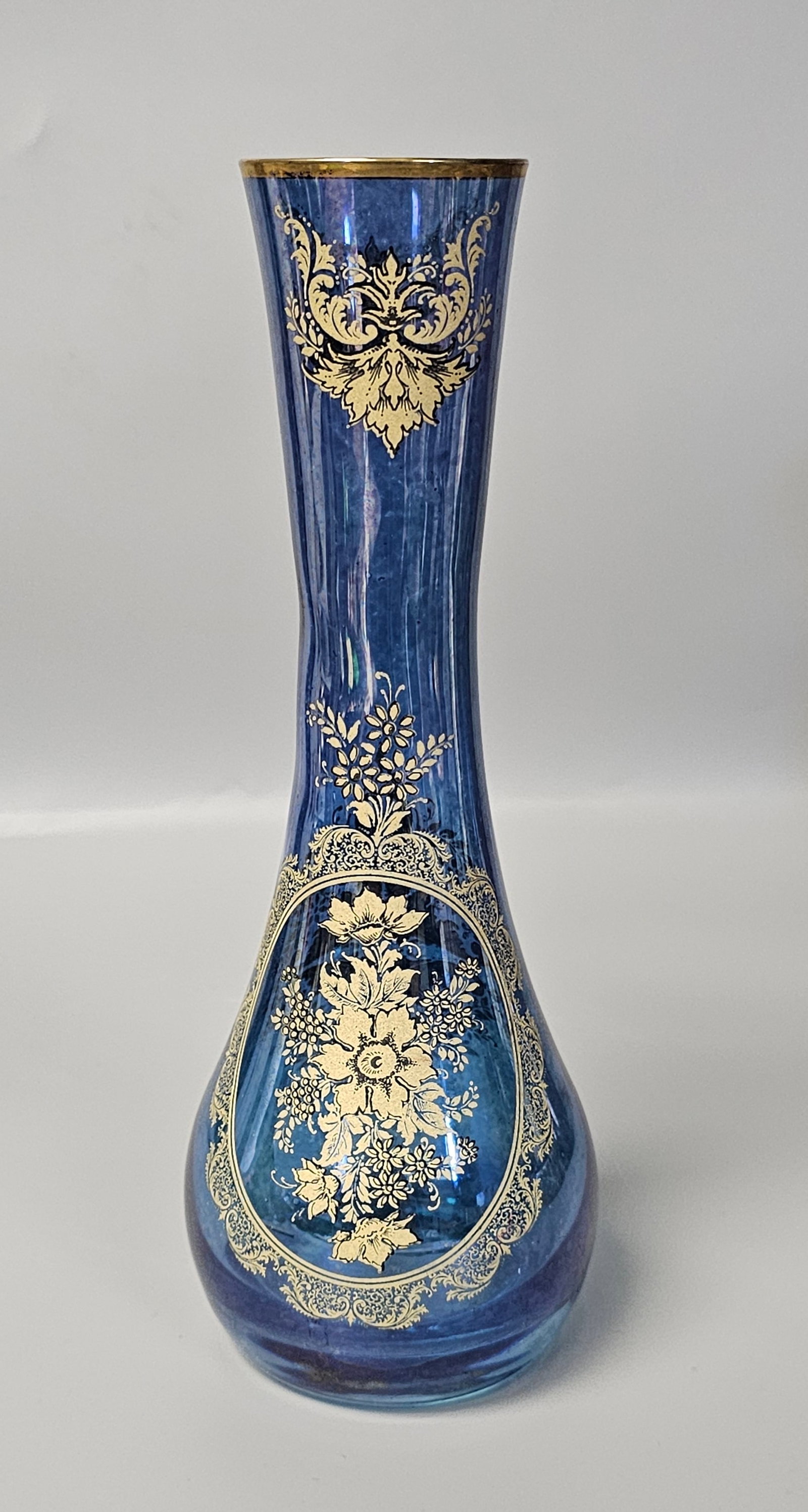 Italian Cobalt Blue Glass Gilt Floral Vase: This mid-20th-century decorative vase is crafted from blown cobalt blue glass. The piece features a tall, slender neck that flares at the rim and tapers into a bulbous, teardrop-shaped base. The exter