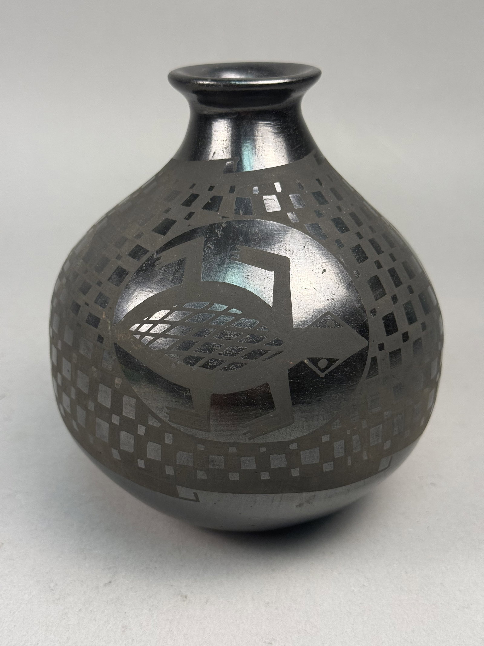 Black-on-Black Mata Ortiz Pottery Vase: This ceramic vessel is a hand-coiled olla or vase from the Mata Ortiz pottery tradition of Chihuahua, Mexico. The piece is signed Graciela Sandoval on the base. It features a globular body with a