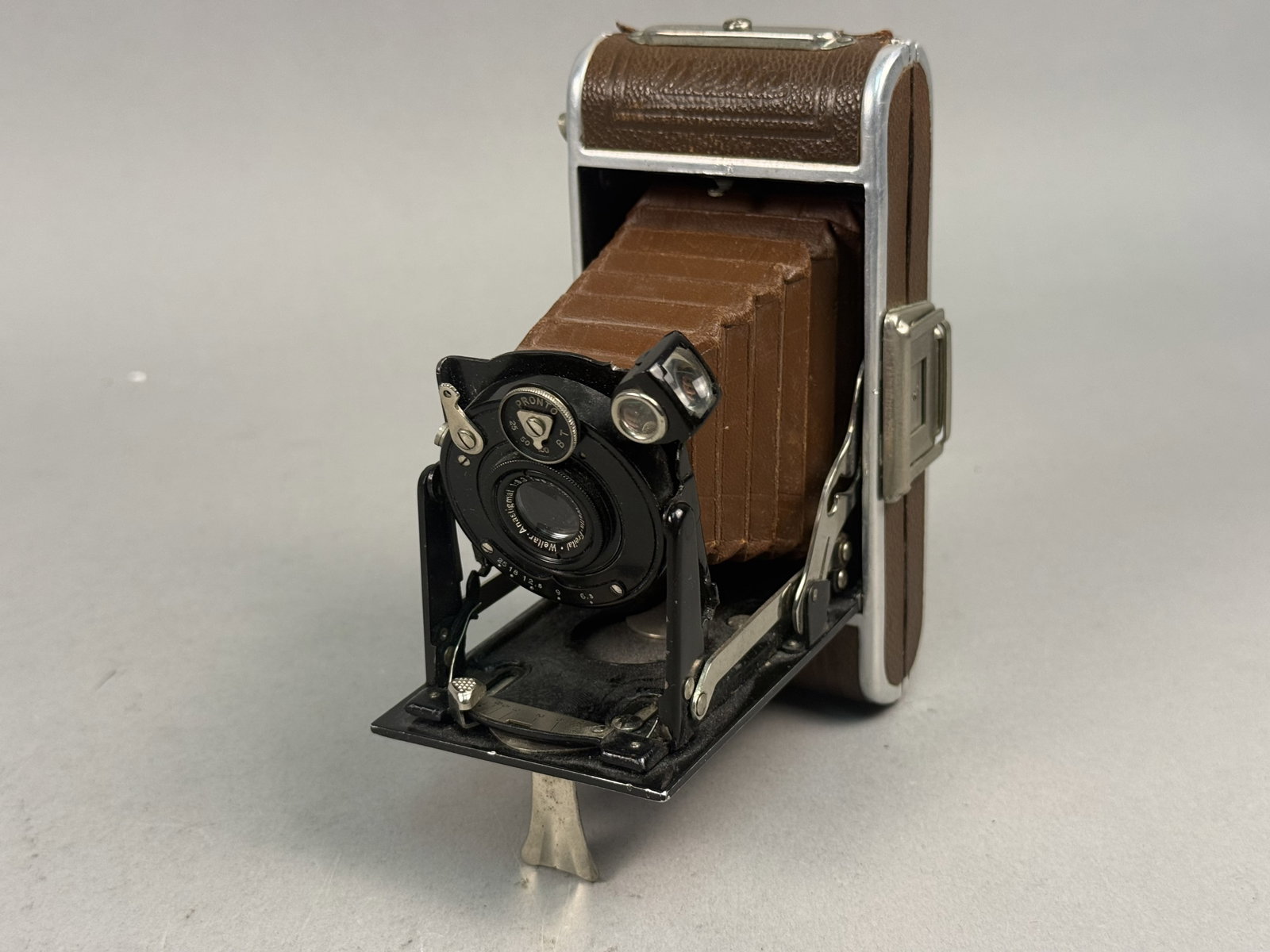 Welta Perle Luxus Brown Leatherette Camera: A Welta Perle Luxus folding roll film camera produced by Welta Kamera-Werke in Freital, Germany, dating to the 1930s. It is equipped with a Weltar-Anastigmat 1:6.3 f=9.0 cm lens mounted in a Pronto