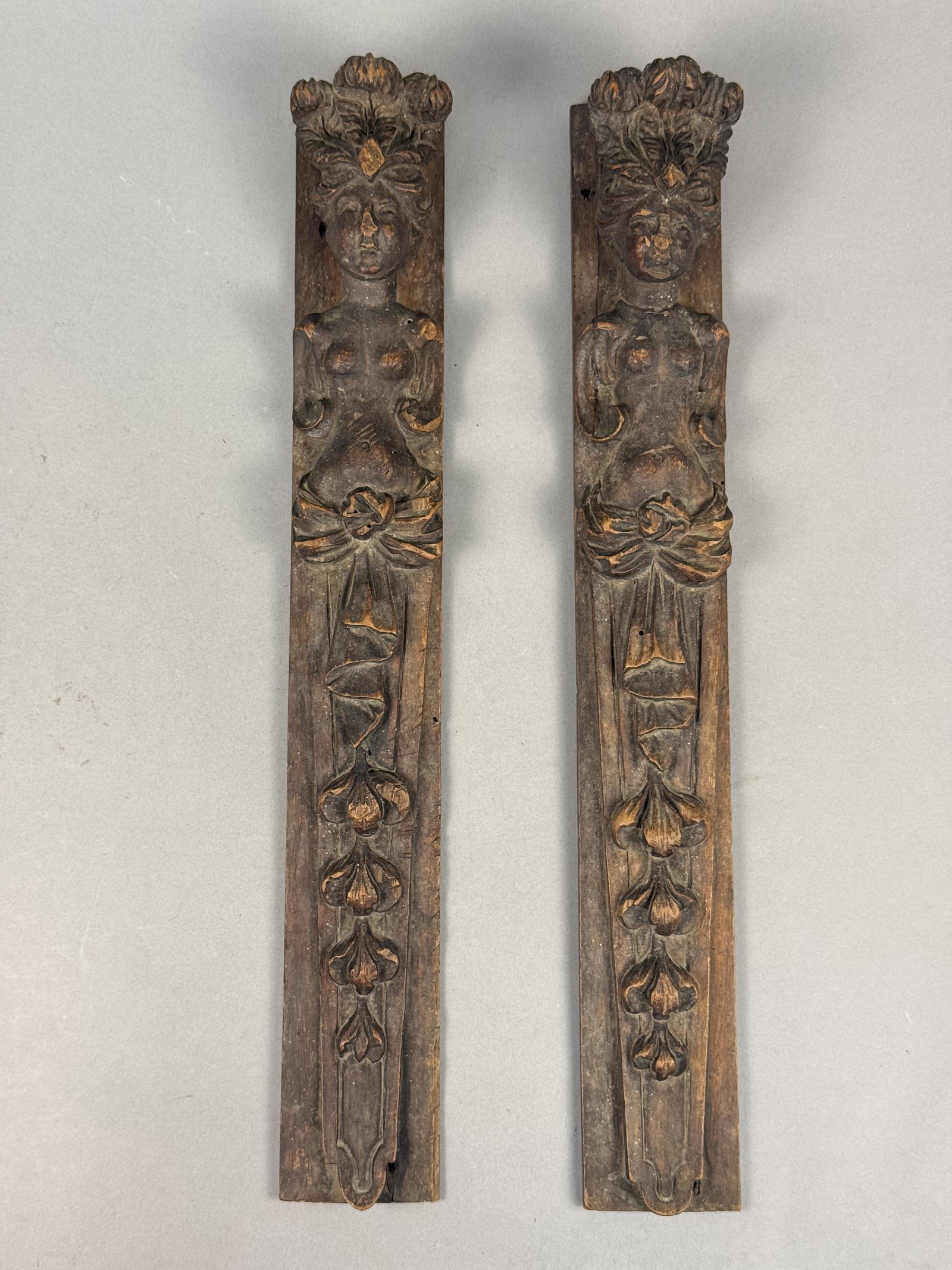 Carved Wood Figural Caryatid Terms: This is a pair of hand-carved hardwood architectural salvage panels featuring high-relief figural carvings in the Renaissance Revival style. The wood exhibits a dark, aged patina. The reverse of each
