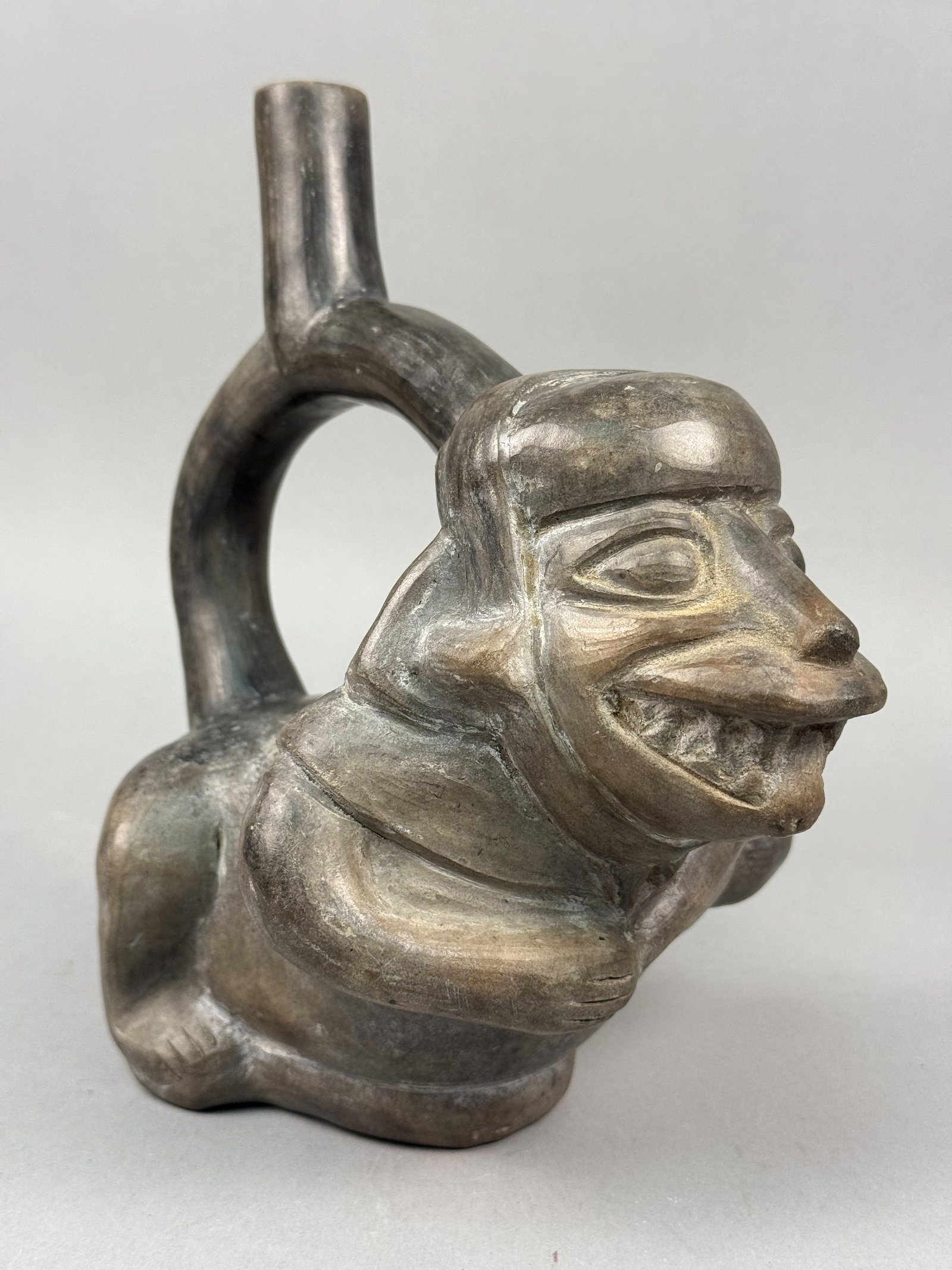 Peruvian Blackware Ceramic Stirrup-Spout Vessel: This ceramic vessel is a contemporary blackware stirrup-spout jar crafted in the style of ancient North Coast Peruvian cultures, such as the Moche or Chimu. The piece is formed from dark clay and
