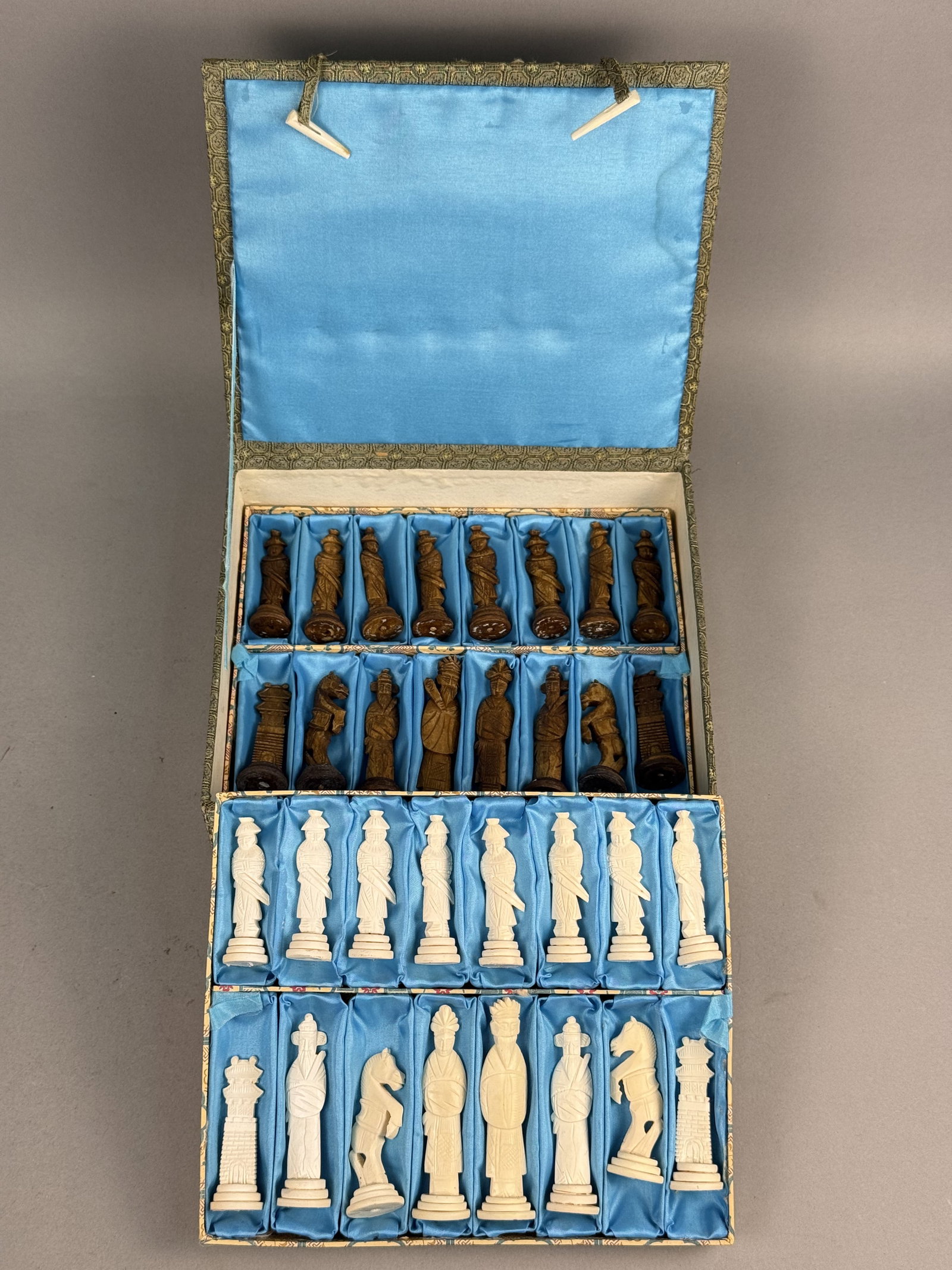 Chinese Carved Bone Chess Set: A complete set of 32 hand-carved bone chess pieces in the traditional Chinese export style. The set is divided into 16 natural off-white pieces and 16 pieces stained a dark brown. The pieces are