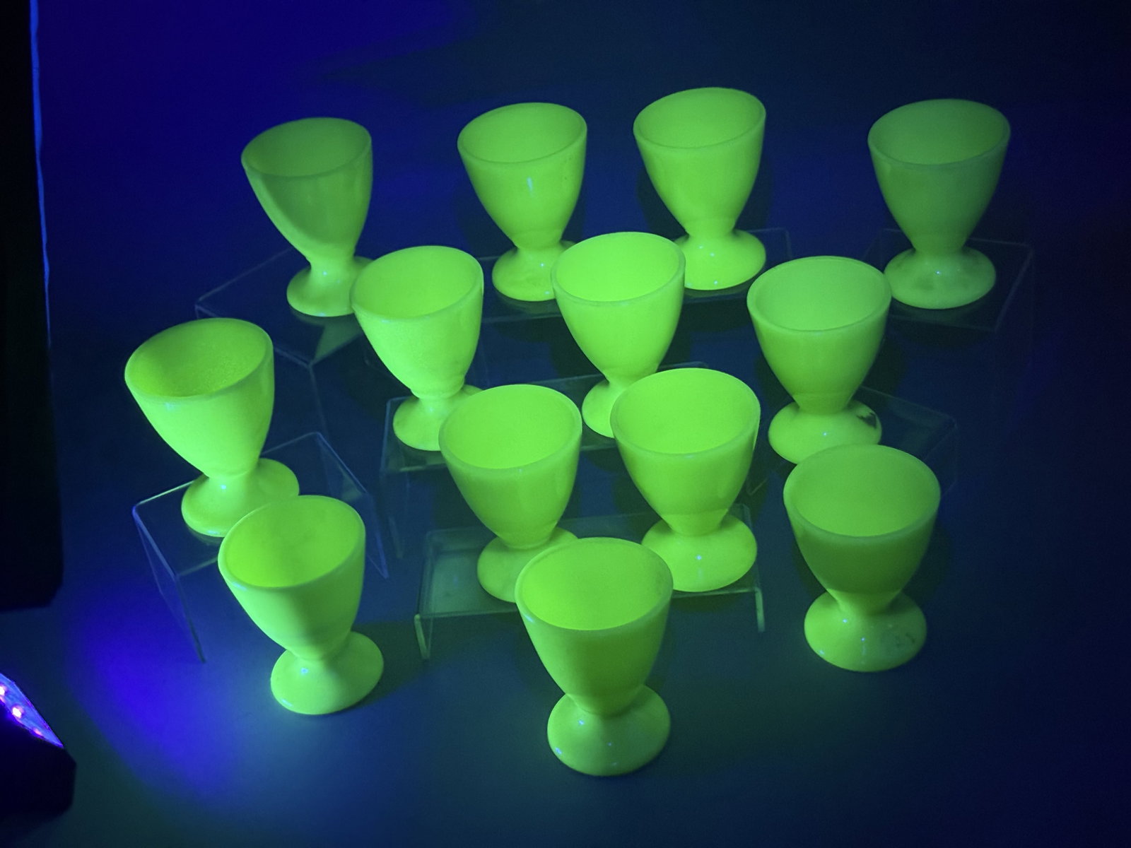 A Set of McKee Jadeite Glass Goblets: These pieces are made of opaque, pale green jadeite milk glass. The glass composition includes uranium, resulting in a strong green fluorescence when exposed to ultraviolet light. Several pieces bear 