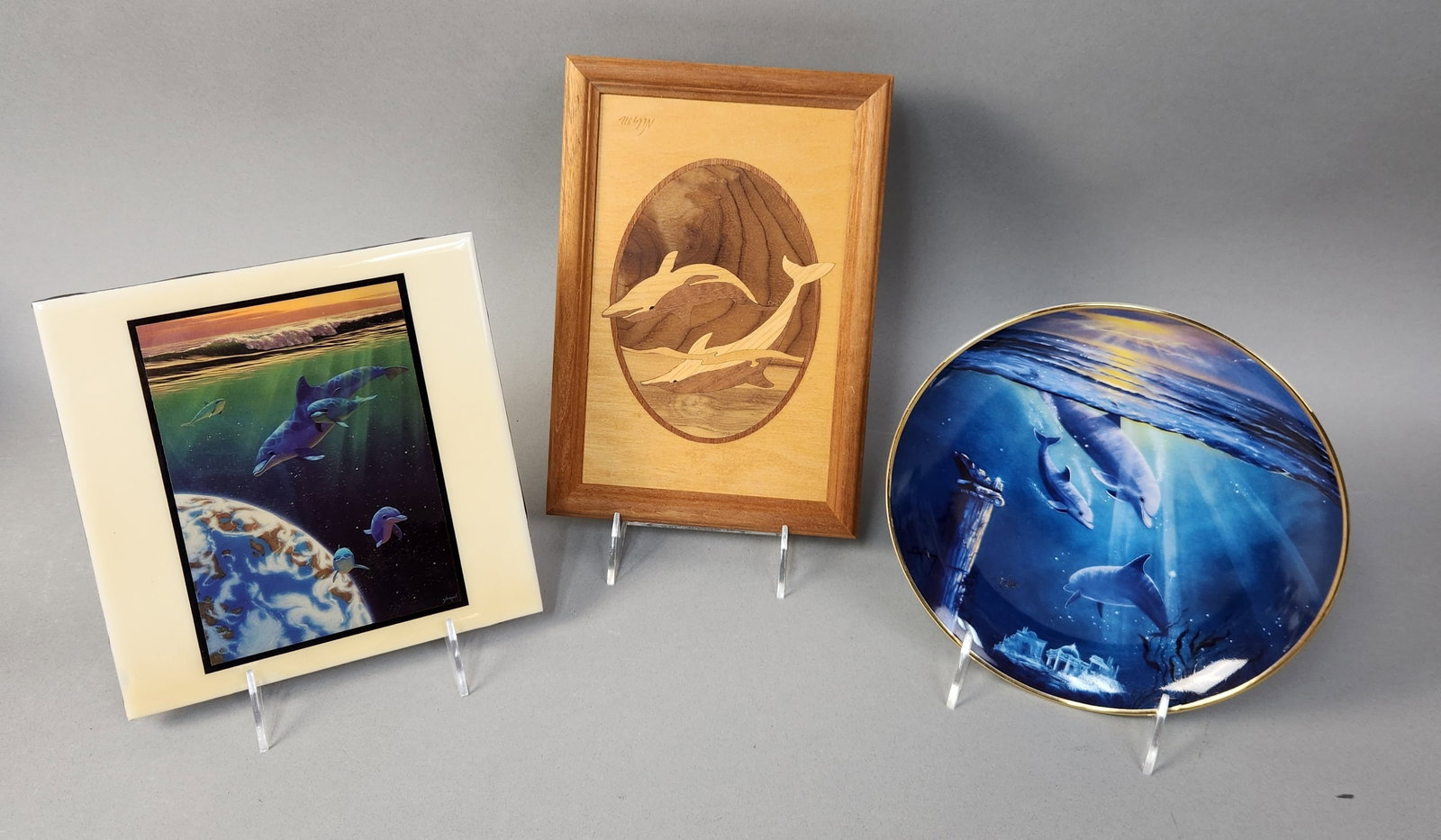 Trio of Dolphin-Themed Decorative Items: This collection consists of three decorative items featuring dolphin imagery. The group includes a square ceramic tile titled Children of the Earth featuring artwork by Schim Schimmel and produced by 