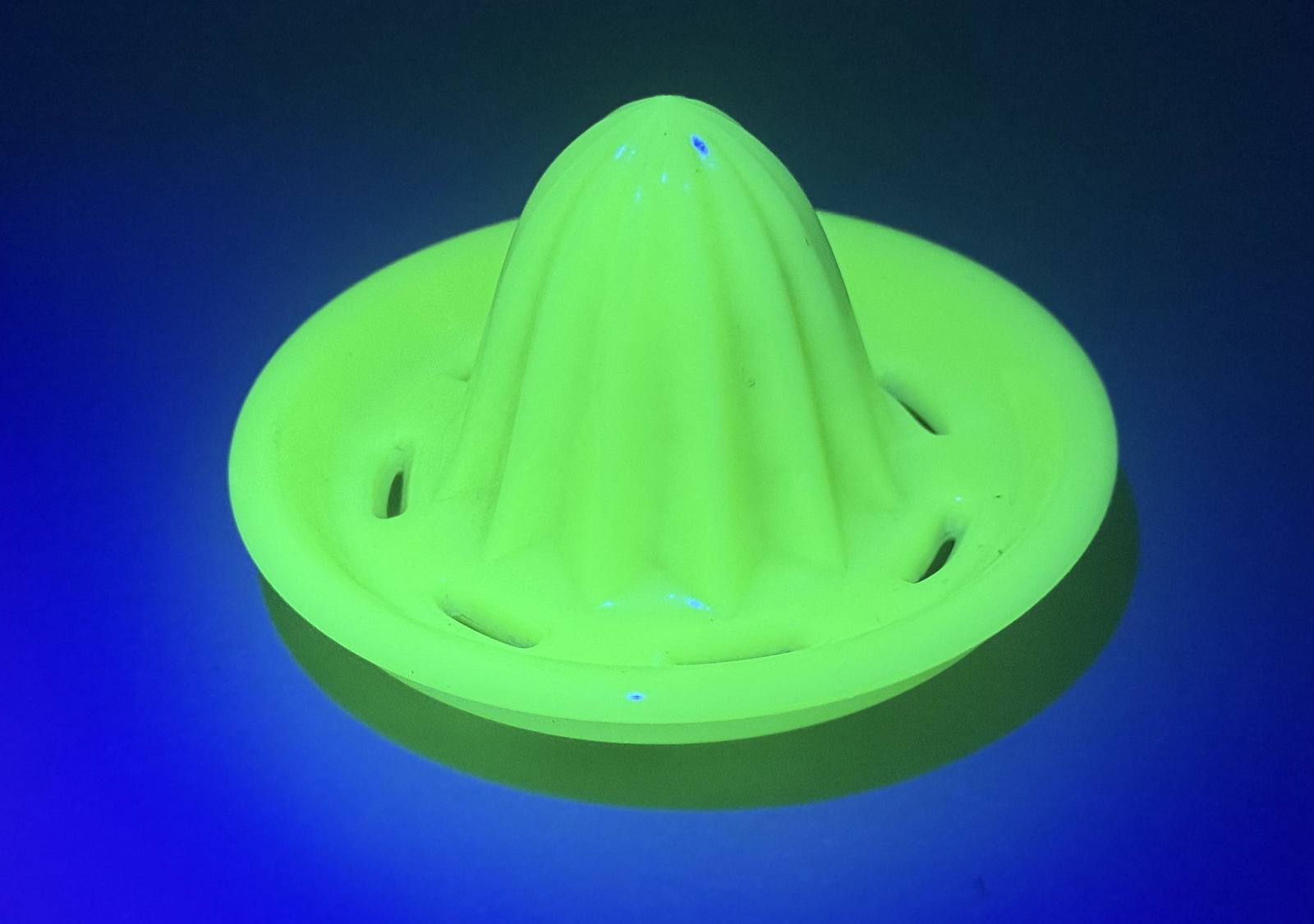 Jadeite Uranium Glass Citrus Reamer Insert: This vintage citrus reamer insert is crafted from opaque green glass, commonly known as jadeite. The material is uranium glass, which produces a bright neon green fluorescence under ultraviolet light.