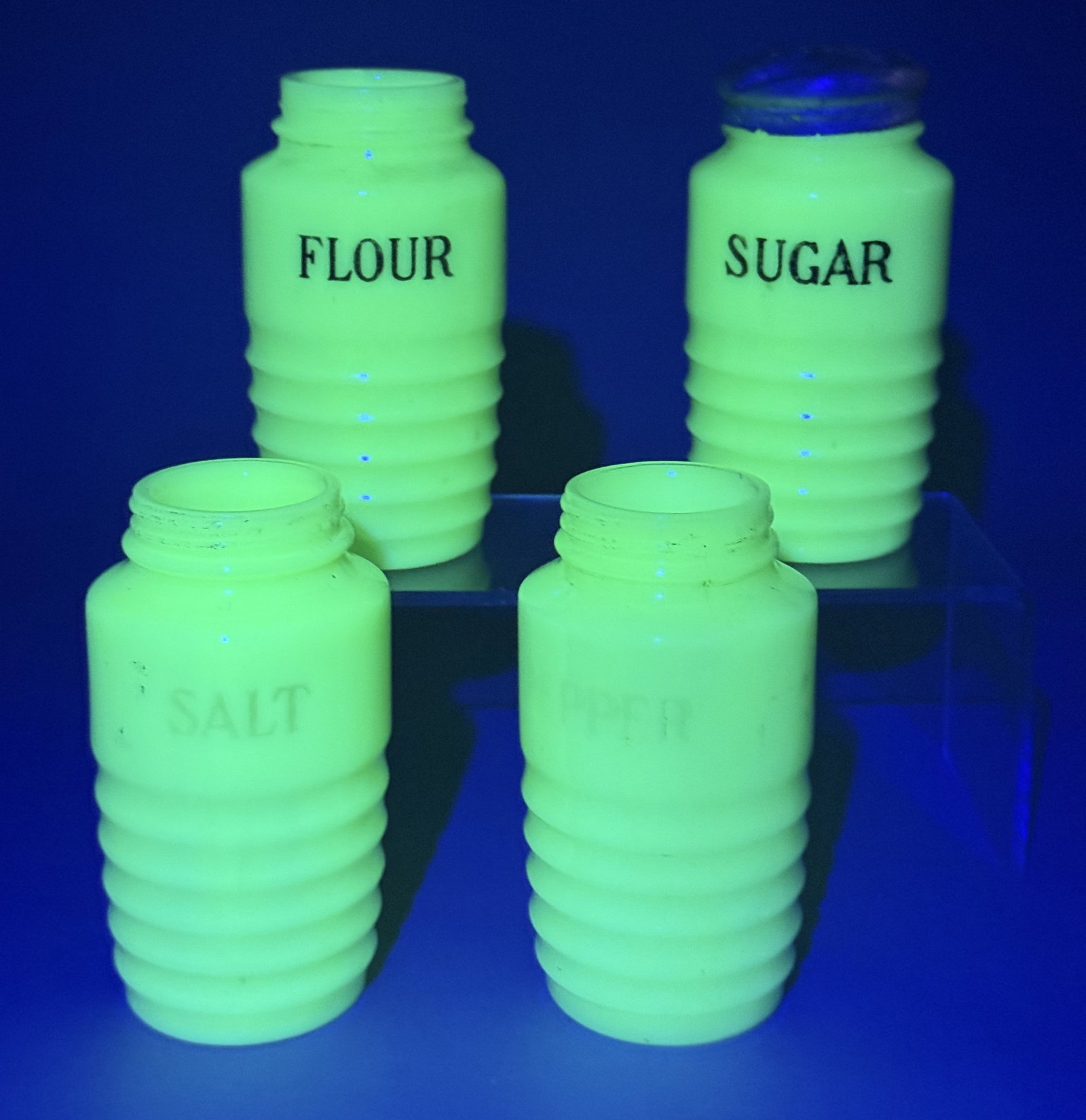 Uranium Jadeite Glass Beehive Shakers: A set of four depression-era kitchen shakers or canisters crafted from opaque green uranium glass, commonly referred to as jadeite. These vessels are attributed to the Jeannette Glass Company and