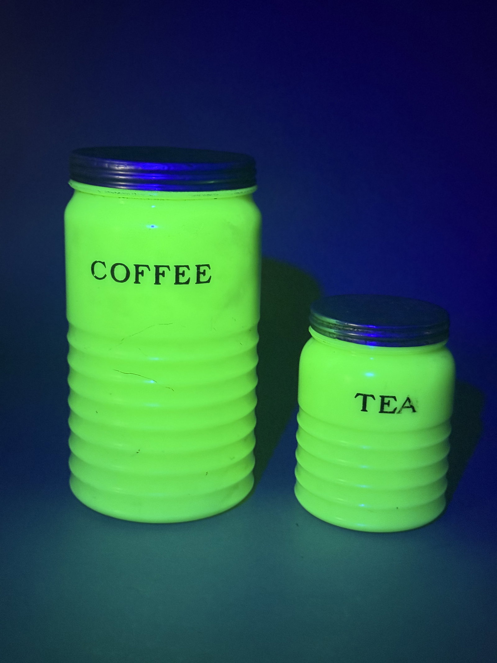 Jeannette Jadeite Uranium Glass Kitchen Canisters: A pair of vintage kitchen canisters manufactured by the Jeannette Glass Company. These items are constructed from opaque green uranium glass, commonly known as Jadeite, which exhibits a bright