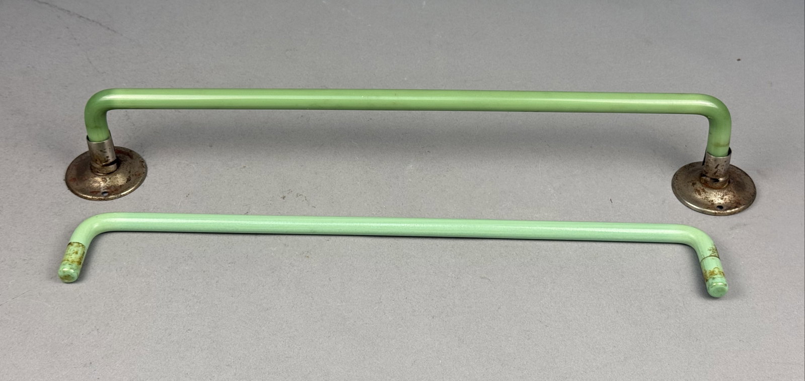 A Pair of Vintage Jadeite Towel Bars: A pair of vintage Art Deco style bathroom towel bars manufactured from solid, opaque light green glass in the style of jadeite. The bars feature a 90-degree bend at each end and a smooth, polished sur