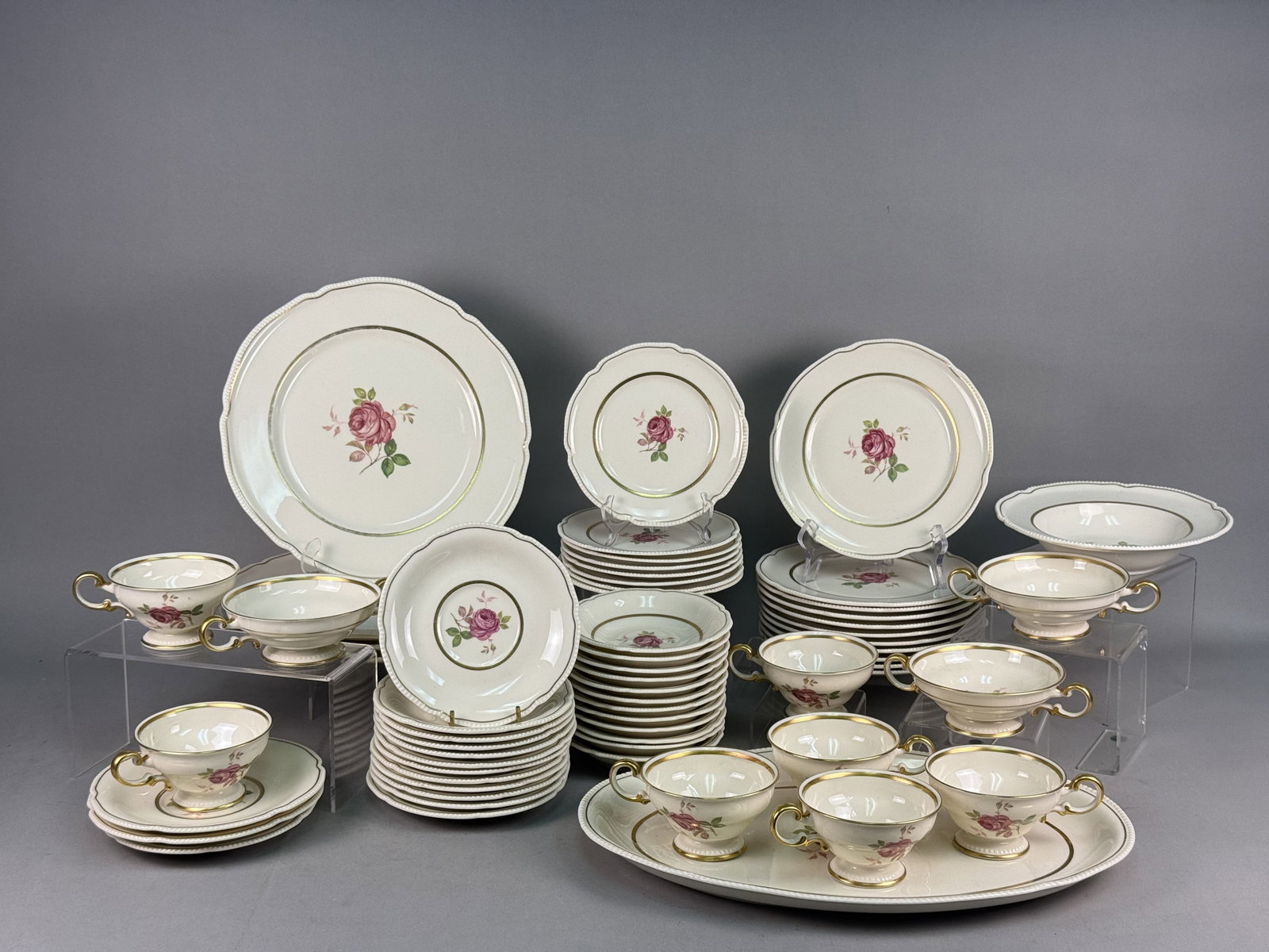 Large Collection of Gilt and Rose Porcelain China: This extensive collection of porcelain dinnerware is designed in the Dolly Madison pattern, widely attributed to Castleton China. The pieces feature a central transfer-printed motif of a pink rose