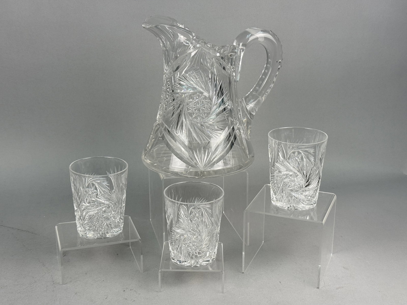 Four American Cut Glass Pitcher and Tumblers: This set of four American Brilliant Period cut glass pieces consists of one pitcher and three matching tumblers. The high-lead crystal construction provides significant weight and clarity. No maker ma