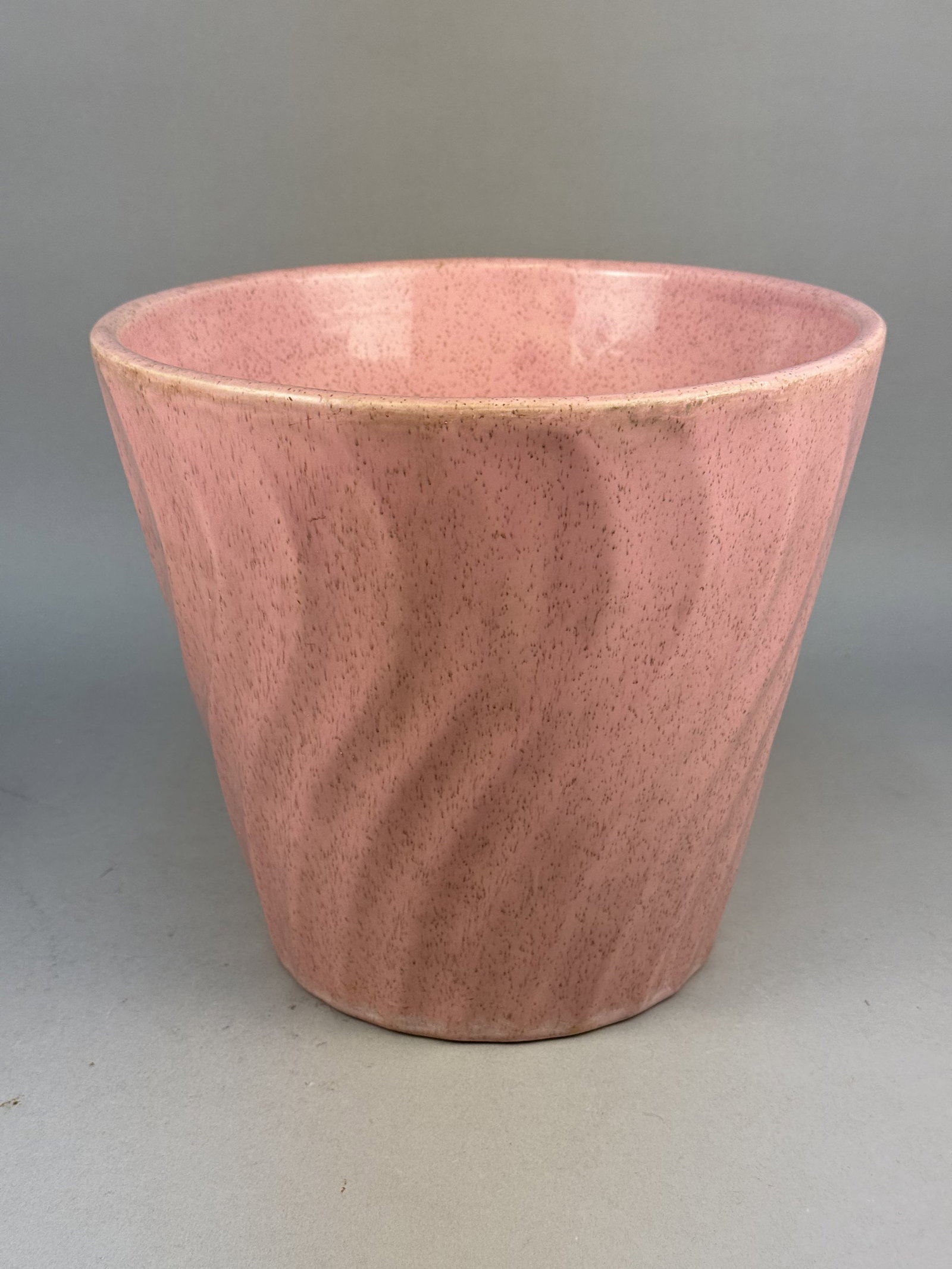 Haeger Potteries Speckled Pink Ceramic Planter: A large mid-century modern ceramic planter manufactured by Haeger Potteries in the United States. The earthenware vessel features a flared conical form with a molded spiral relief or swirl pattern on 