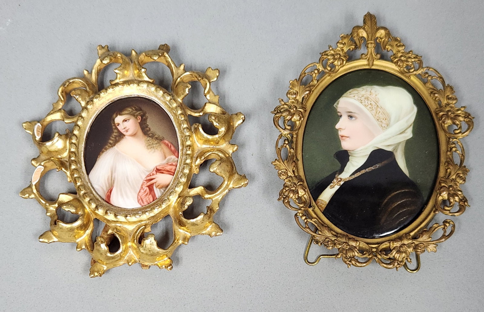 Painted Porcelain Portrait Plaques: Two Continental hand-painted porcelain portrait miniatures. The first plaque depicts a woman in profile wearing a white wimple and a dark gown with a cross pendant, rendered against a dark green groun