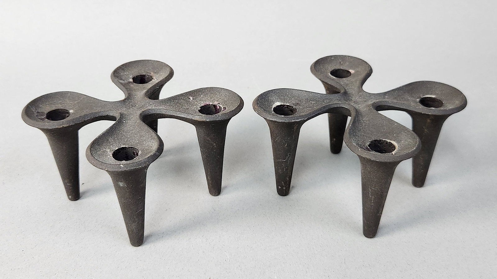 Dansk Cast Iron Candle Holders Jens Harald Quistgaard: This pair of four-light candle holders features a sculptural, organic cross-form design characteristic of mid-century Danish modernism. The underside of the central bridge on both pieces is stamped wi