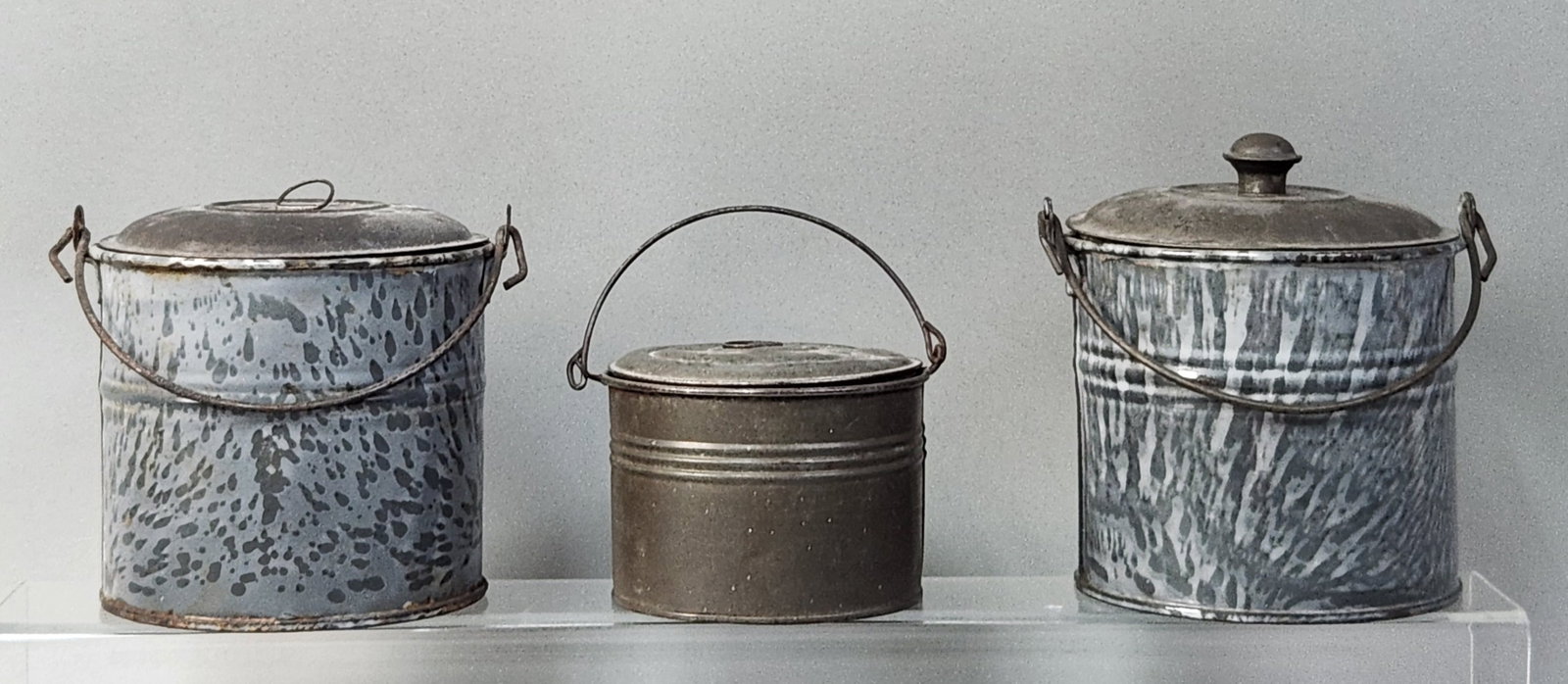 American Graniteware Canisters: An assortment of three vintage cylindrical lidded metal containers, commonly utilized for domestic storage or as lunch and berry pails. Canister 1: 6 inches (height to rim) Canister 2: 5.25 inches (he