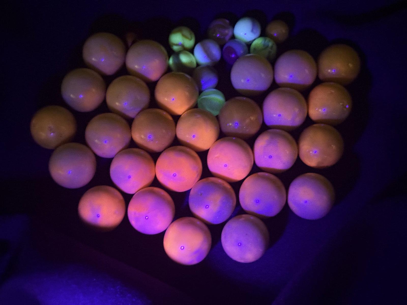 Vintage Cadmium and Uranium Glass Marbles: This collection consists of 39 vintage machine-made glass marbles. The primary group features large shooter or boulder sized marbles made of opaque yellow-to-cream custard-style glass, with some examp