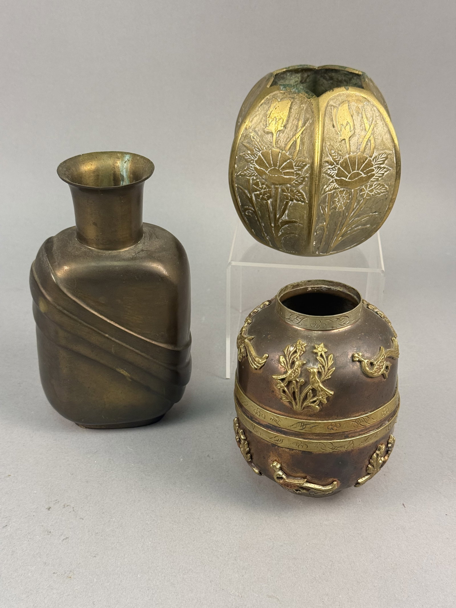 3 Mixed-Metal Vessels Art Deco & Repouss?© Examples: A trio of mid-20th-century decorative metal vessels of Indian origin. The first vessel is a brass vase of rectangular profile with rounded corners, a slender neck, and a flared circular rim. The body 