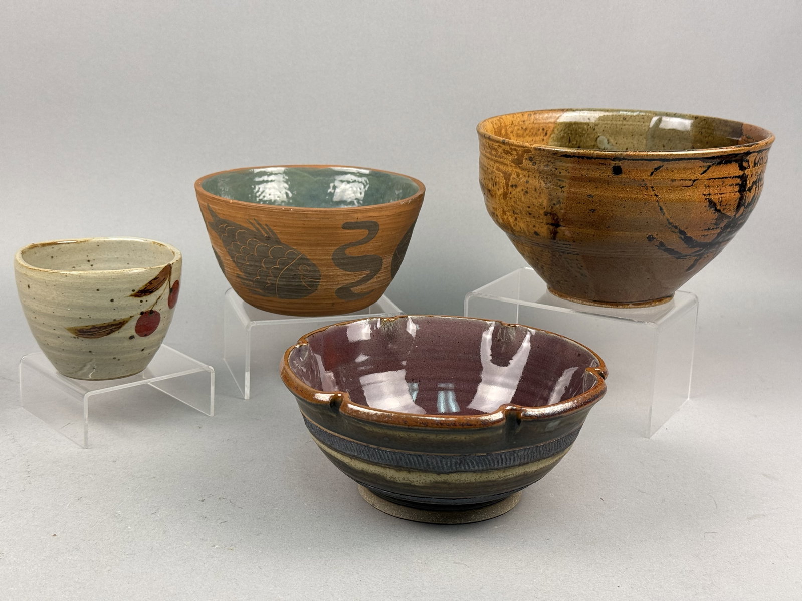 Contemporary American Studio Pottery Bowls & Cup: A collection of four contemporary American studio pottery pieces, all executed in various stoneware bodies and glaze styles. The first piece is a large, deep bowl with tapered sides featuring a multi-