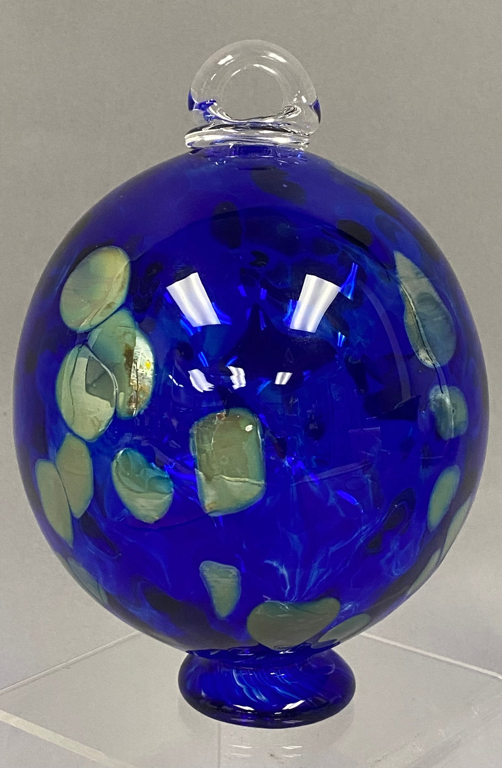 Bohemia Hand Blown Cobalt Blue Glass Orb: This hand-blown art glass orb ornament originates from the Bohemia region of the Czech Republic. The piece is crafted from vibrant cobalt blue glass featuring scattered, irregular pale green macchia