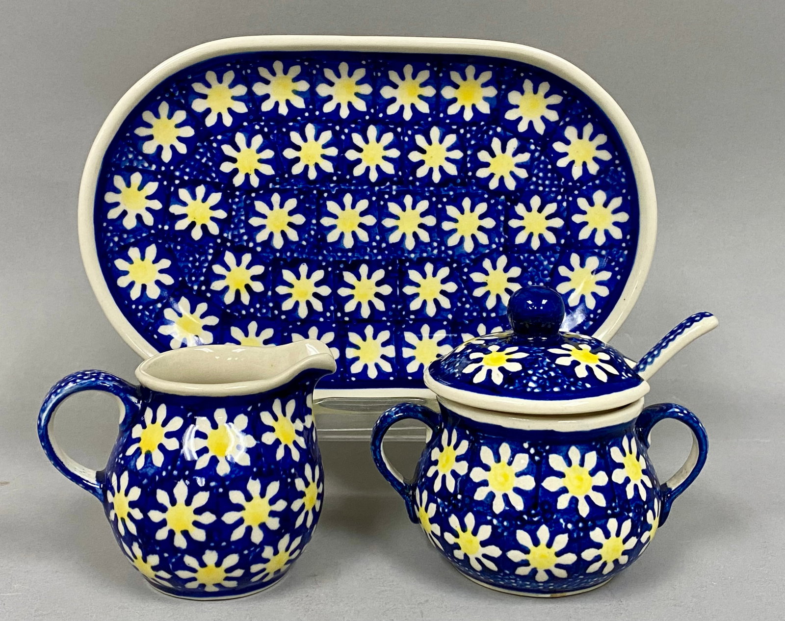 Polish Pottery Cream and Sugar Service: This set of Polish stoneware is produced by Manufaktura w Boleslawcu and features the Morning Daisy pattern. The set includes a cream pitcher, a lidded sugar bowl, an oval tray, and a small serving