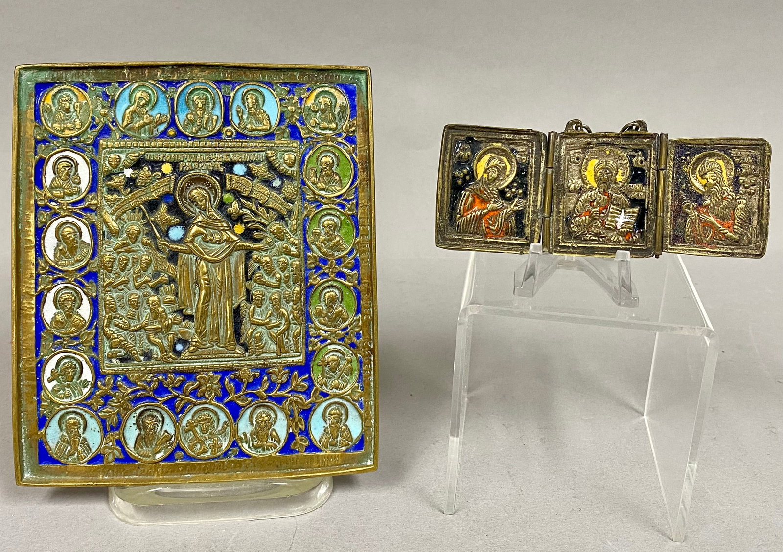 2 Russian Orthodox Brass & Polychrome Enamel Icons: This lot consists of two Russian Orthodox cast brass icons featuring polychrome enamel work, dating to the 19th century. The larger rectangular icon depicts the Mother of God, Joy of All Who Sorrow