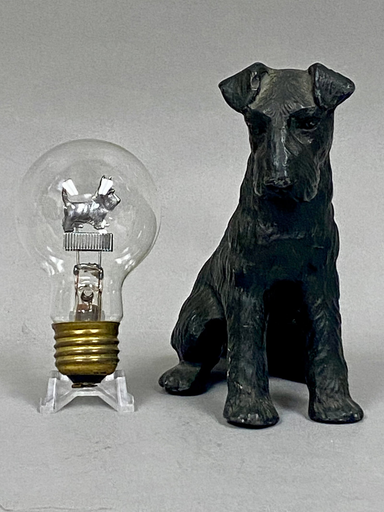 Scotty Aerolux Glow Lamp & Cast Metal Figurine: This lot comprises two vintage collectibles featuring the Scottish Terrier dog breed. The first item is a specialty gas-discharge glow lamp produced by the Aerolux Light Corporation. The interior of
