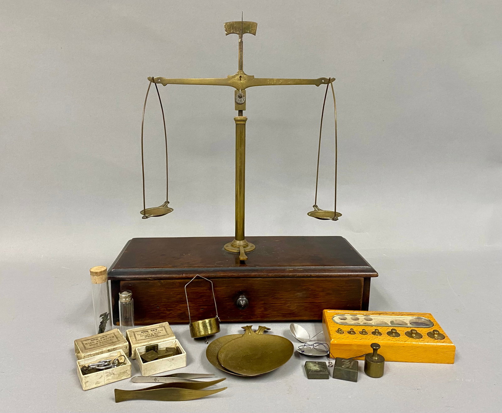 Antique Brass Apothecary Balance Scale & More: This lot features an antique apothecary or analytical beam balance scale constructed of brass and mounted on a mahogany-finished wooden base. The central cylindrical brass pillar is equipped with a