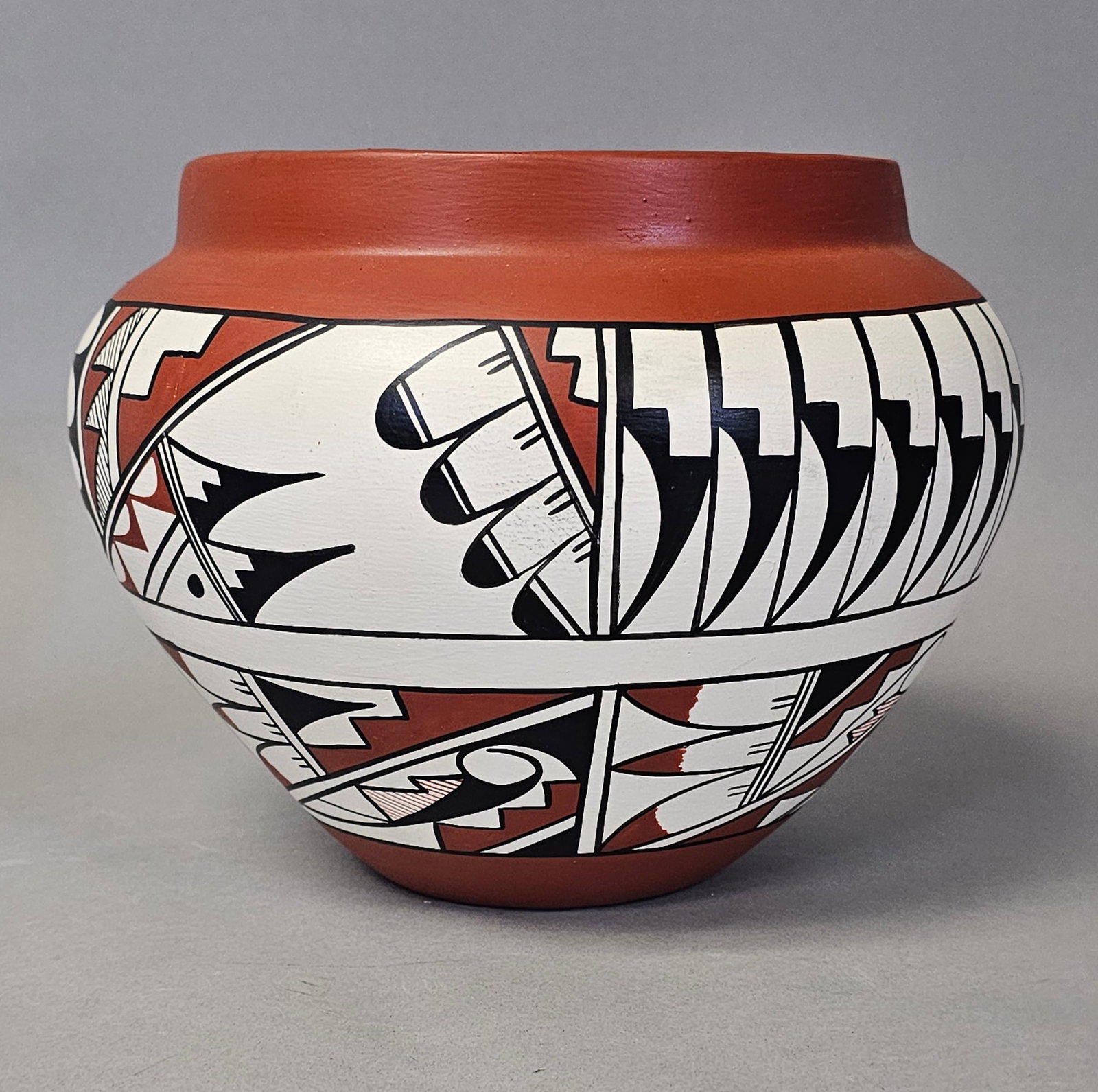 Jemez Pueblo Polychrome Pottery Jar: A handmade Jemez Pueblo earthenware jar signed by E. Tafoya featuring polychrome geometric motifs. The vessel is decorated with black and red slip over a white ground, displaying stylized feathers and