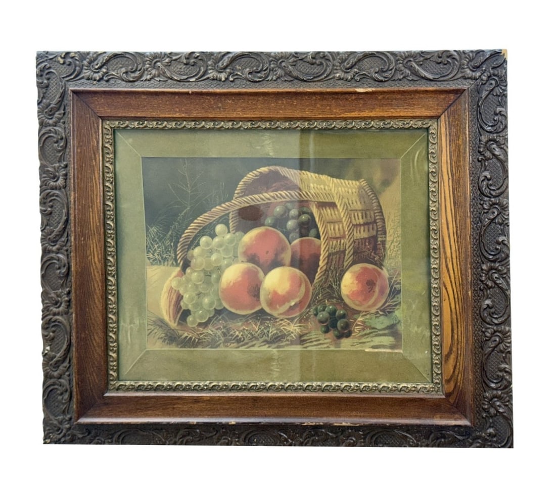 A Basket of Peaches Framed Lithograph: This late Victorian color lithograph on paper depicts a still life of peaches and clusters of green and purple grapes spilling from a tipped-over woven wicker basket. This composition is based on a