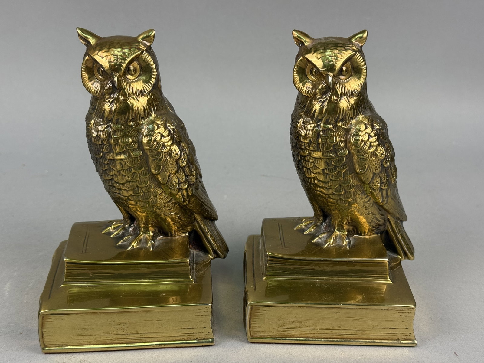 Philadelphia Mfg. Co. Brass Owl Bookends: This pair of cast brass bookends by Philadelphia Mfg. Co. features detailed owl figures perched atop stacked books. Each base is cast with the word HISTORY on the spine and retains the original manufa