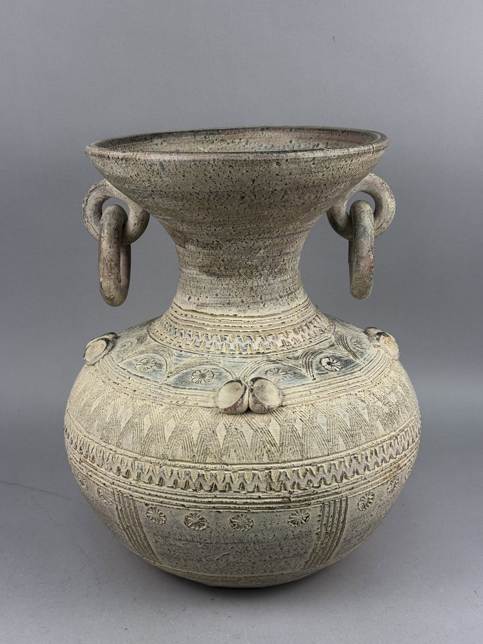 Large Southeast Asian Ring-Handled Jar: A large stoneware vessel featuring a globular body, a constricted neck, and a widely flared basin rim. The jar is decorated with incised and impressed geometric patterns, including floral sunbursts