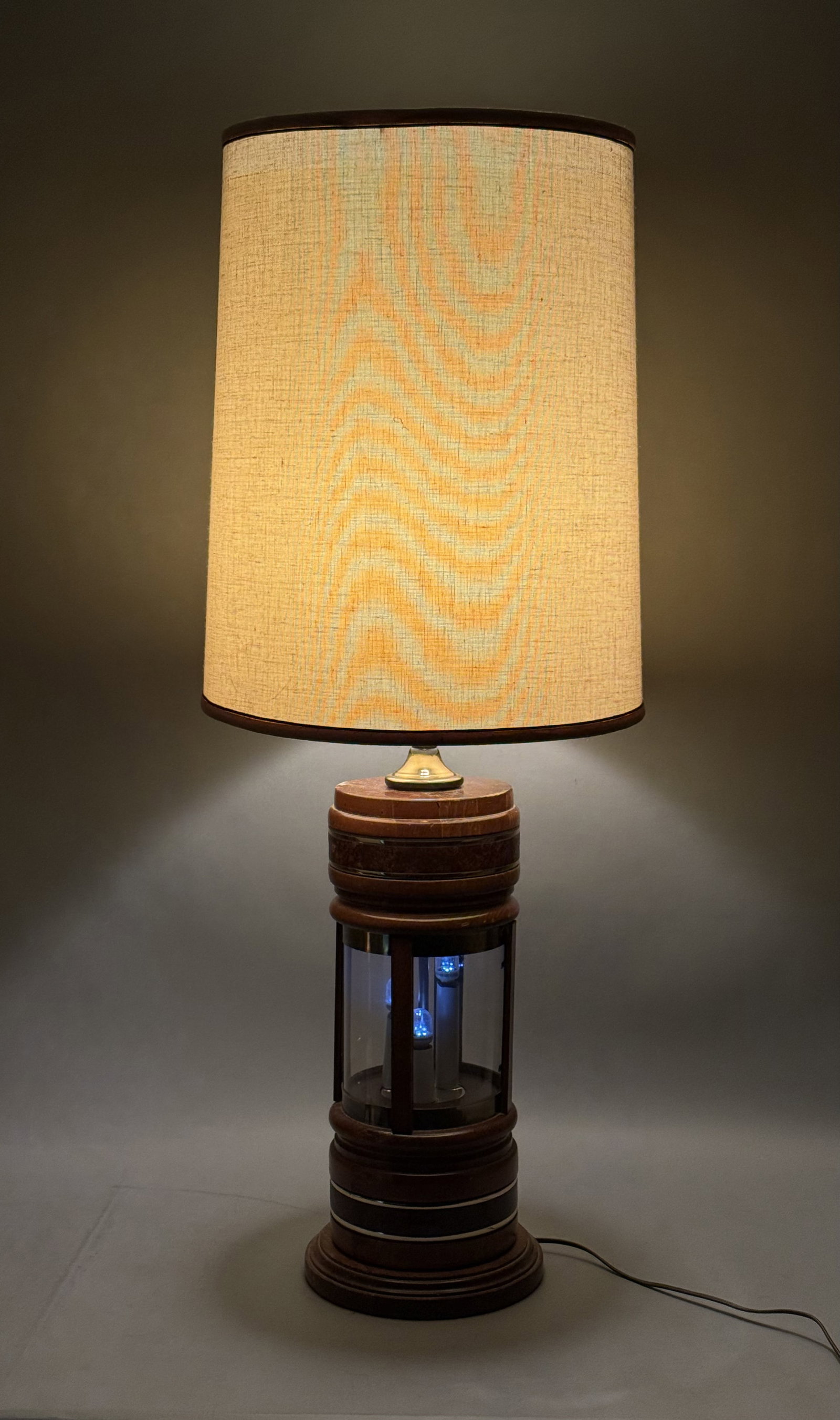Mid-Century Wood and Brass Night-Light Table Lamp: This monumental table lamp features a turned wood and brass-toned base accented with bands of burl wood veneer. The central glass cylinder houses a three-socket night-light assembly, topped by a tall
