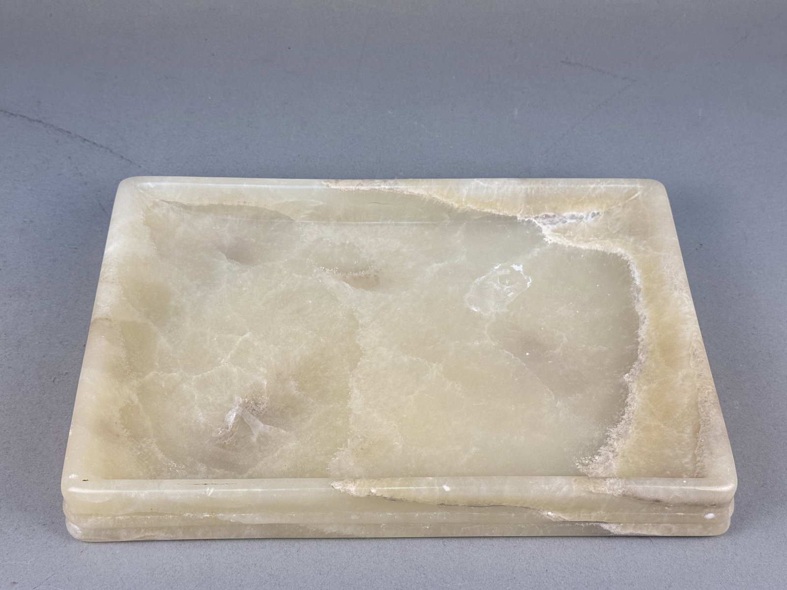 Frontgate Carved Onyx Tray: A rectangular carved onyx tray by Frontgate featuring a polished finish with natural cream, tan, and light brown variegated banding throughout. The tray is designed with a stepped exterior base and a