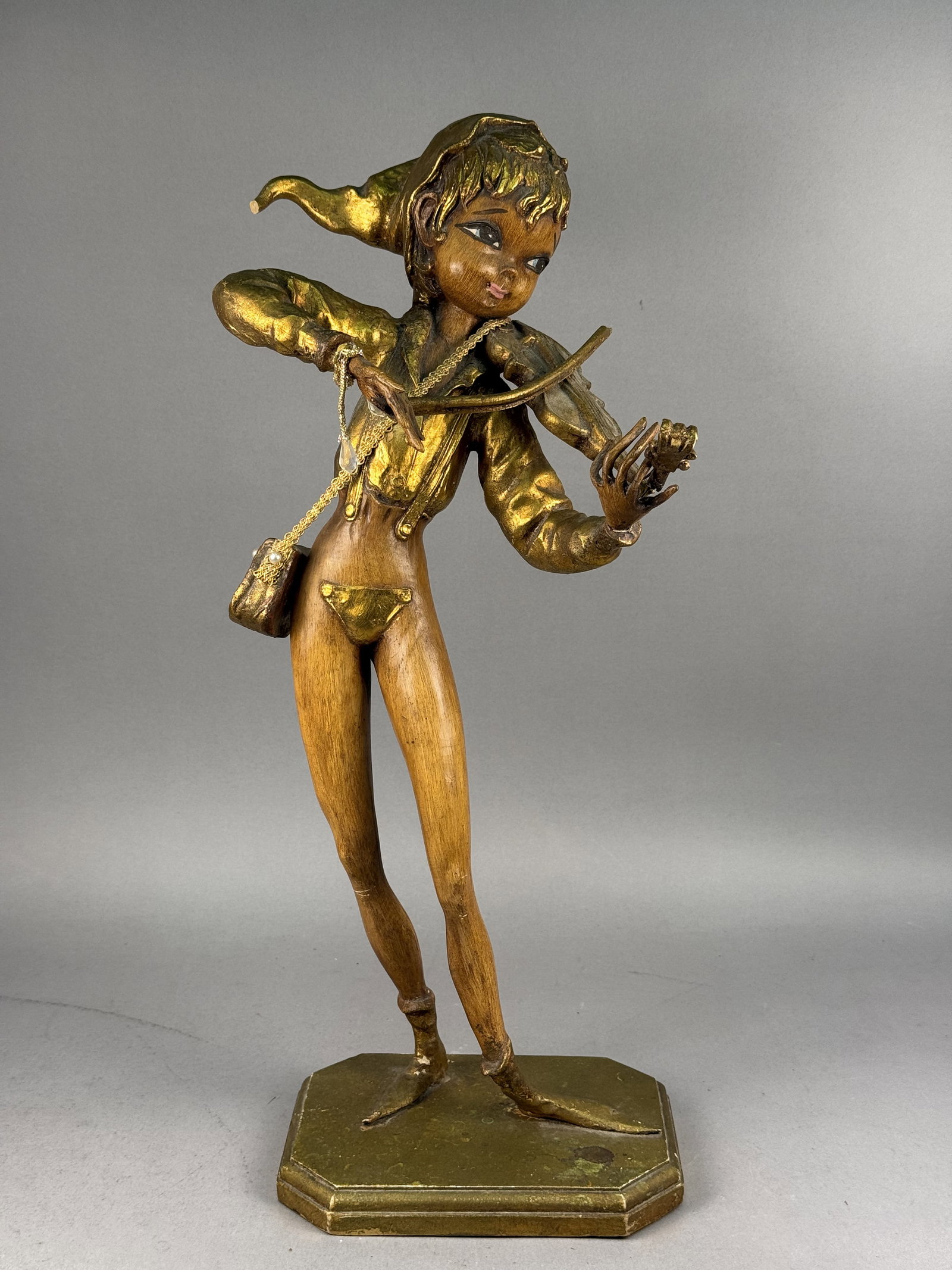 Mid-Century Gilt Wood Elf Violinist: A large mid-century carved wood figurine depicting a whimsical elfin youth playing a violin. The figure features a natural stained wood finish to the face and limbs, while the clothing, hat, and