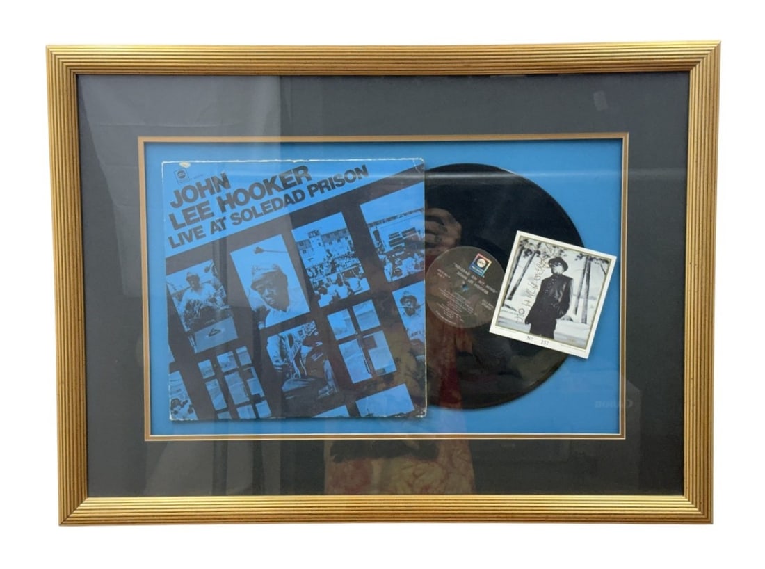 Framed John Lee Hooker Signed Memorabilia: This professionally framed memorabilia display features the work of legendary American blues musician John Lee Hooker. The arrangement includes the 1972 album Live at Soledad Prison with its original