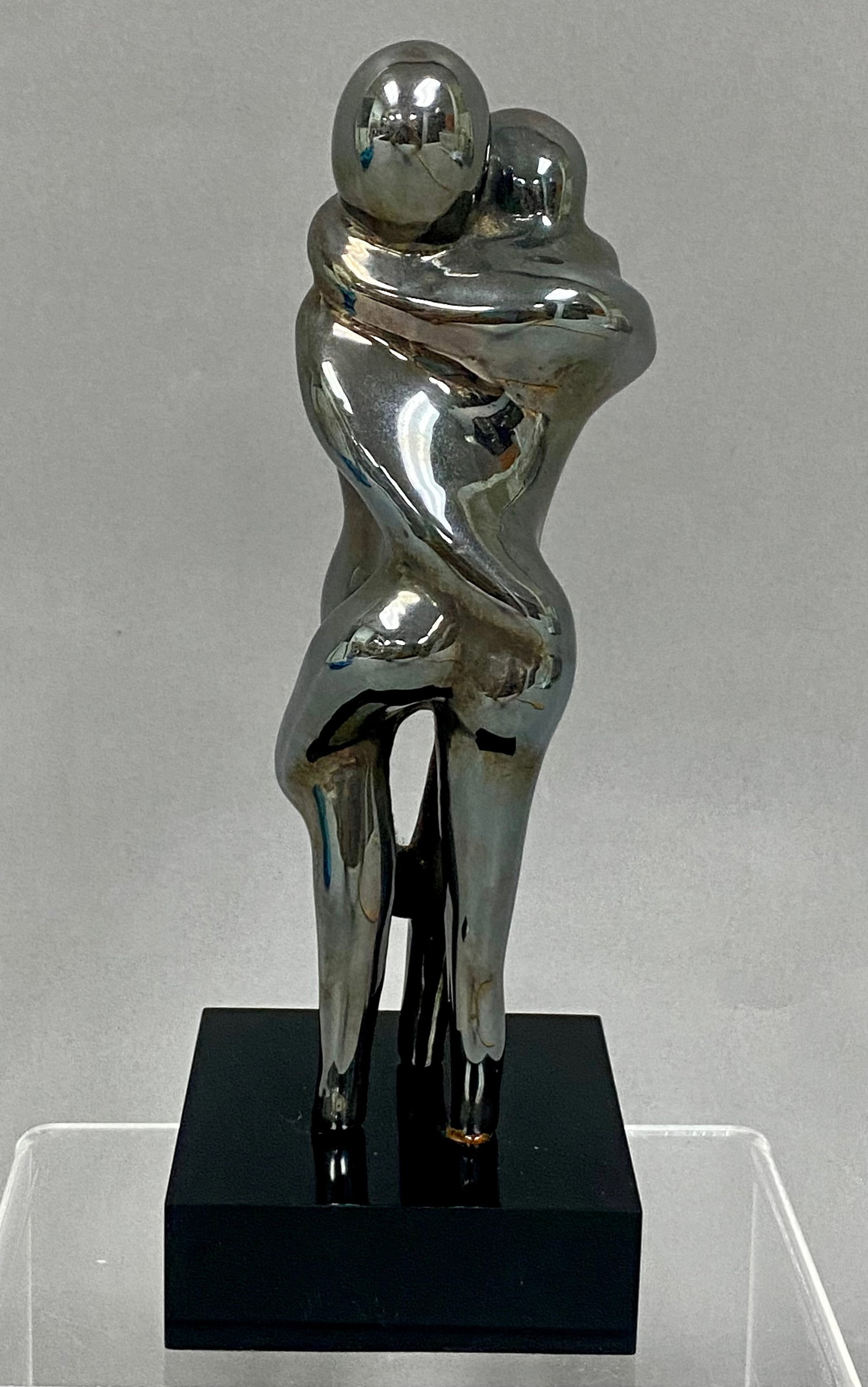 Modernist Silvered Metal Sculpture Embracing Lovers: Modernist-style 7.5inch tall table sculpture depicting an abstract, intertwined couple in a romantic embrace. The fluid, faceless figures are rendered with smooth lines and a highly polished,