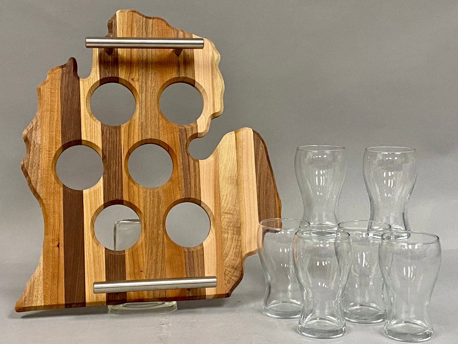 Handcrafted Michigan Wooden Tray 6 Glencairn Glasses: Crafted from striped mixed hardwoods, the tray is shaped like the Lower Peninsula of Michigan and has brushed-metal handles. Measures 11" wide by 13" tall & has six perfectly sized recessed cutouts
