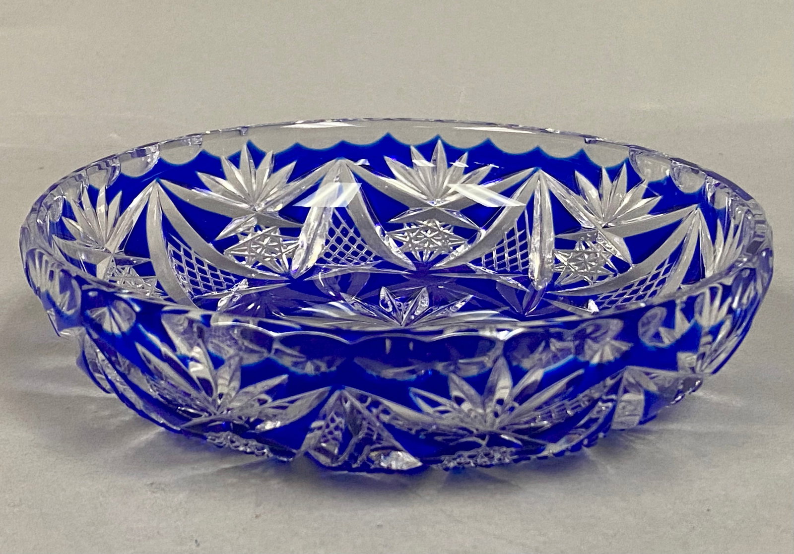 Cobalt Blue Cut-to-Clear Crystal Bowl: This decorative bowl is crafted from cased lead crystal featuring a cobalt blue overlay cut to clear, a style characteristic of Bohemian glassmaking traditions. The body is decorated with an