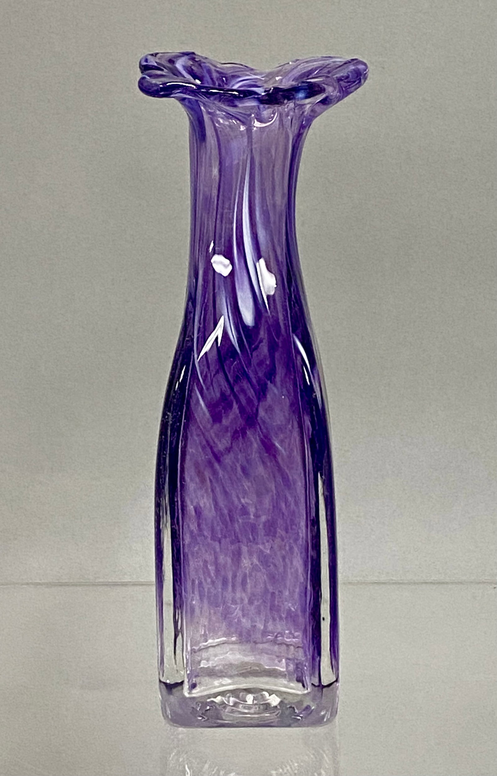 Amethyst and White Swirled Studio Art Glass Vase: This hand-blown studio art glass vase is composed of amethyst-colored glass with swirled white and translucent inclusions. The vessel features a square base that tapers into a slender, twisted neck